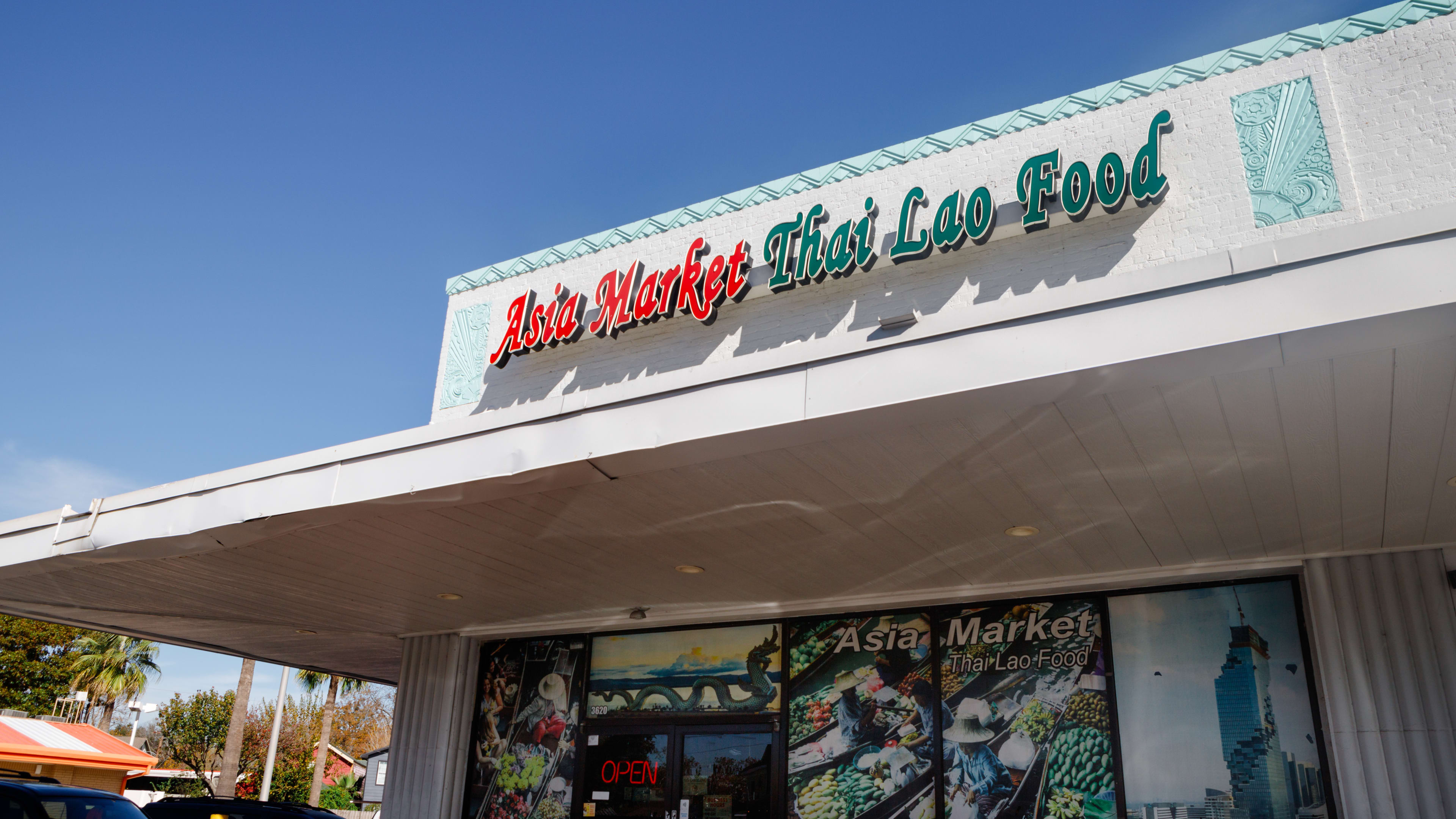 strip center corner with neon sign reading asia market thai lao food