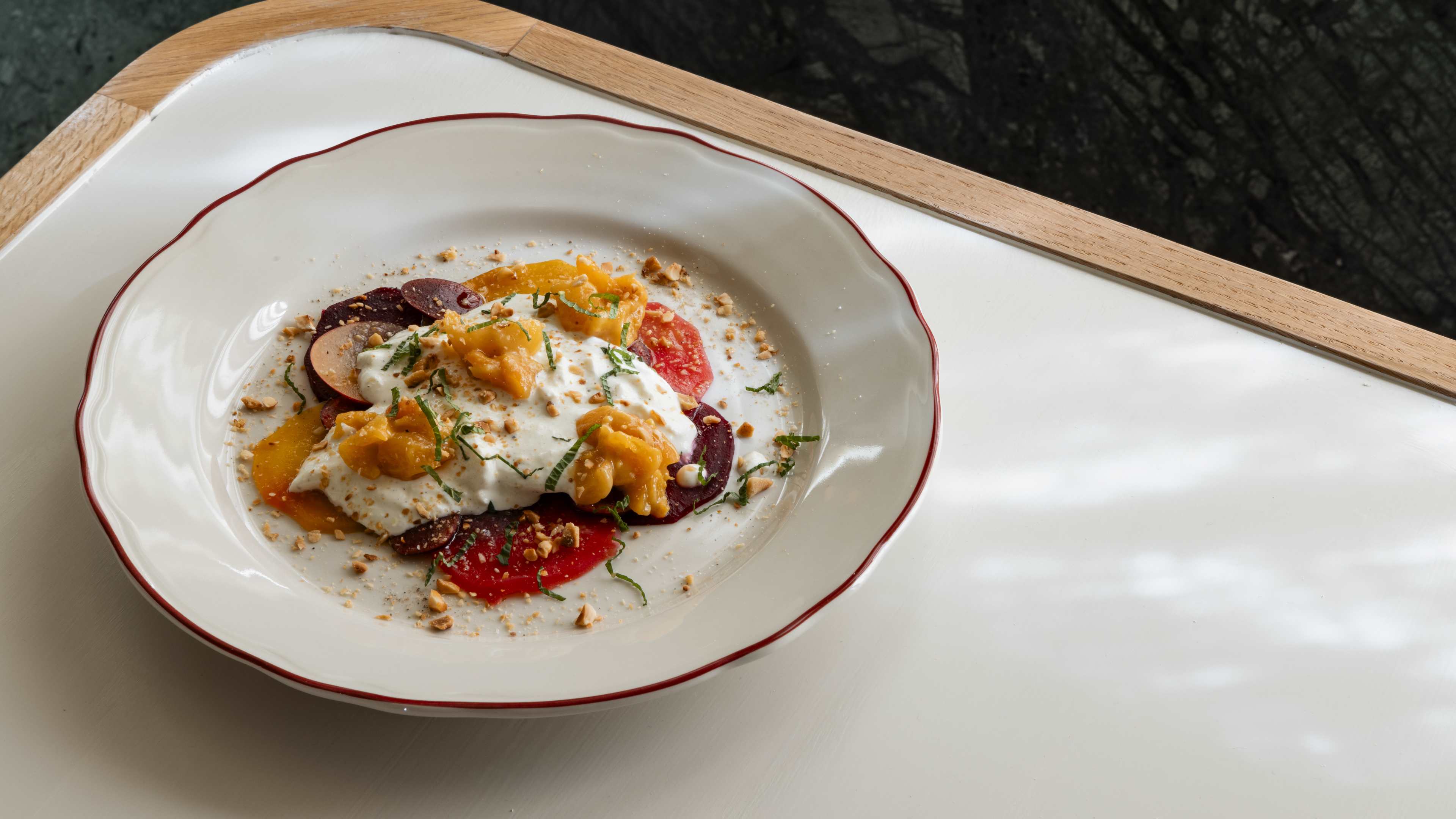 A bowl of straciatella with apricot, beets, and hazelnuts.