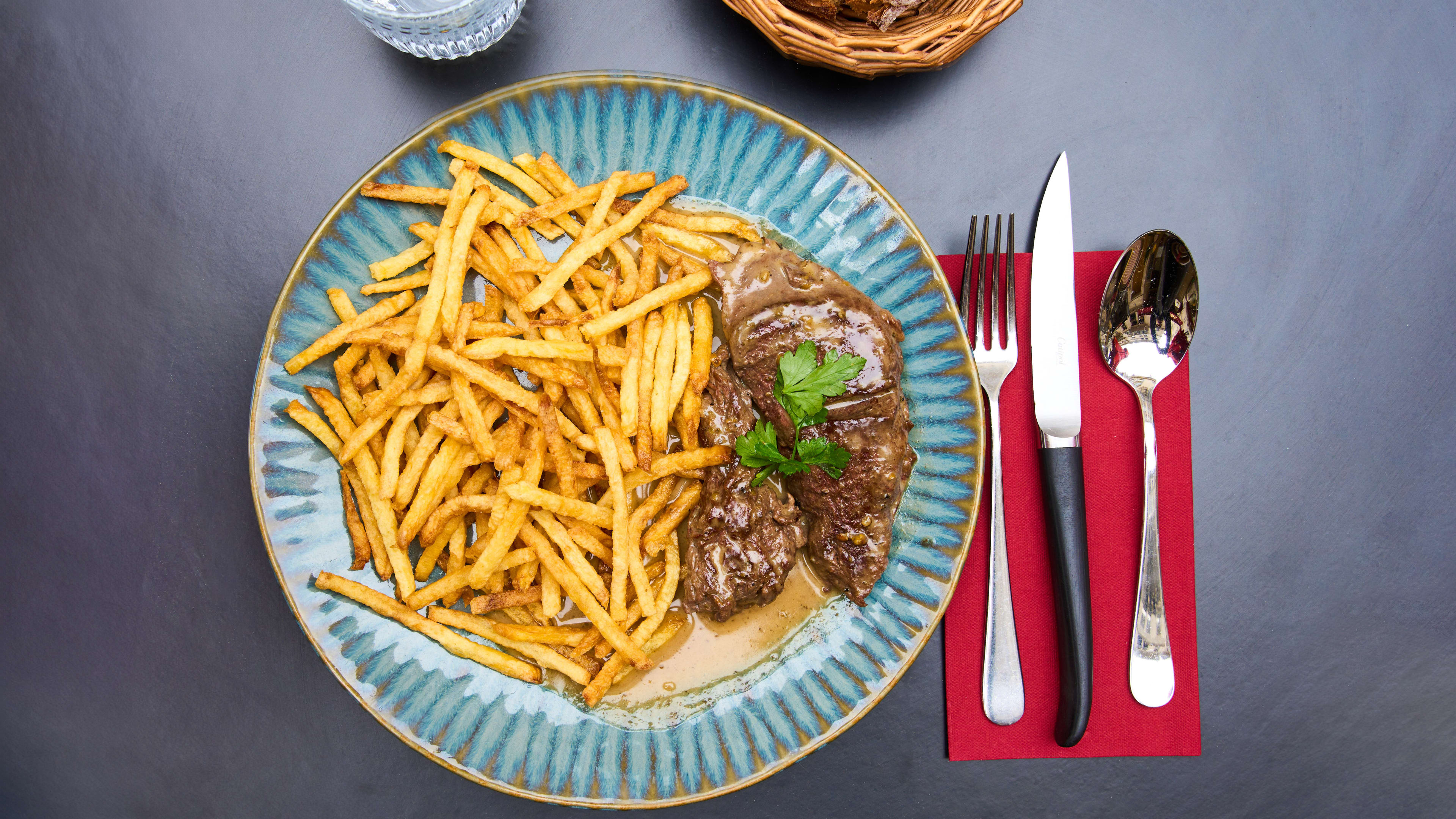 Steak frites topped with fresh parsley at Bistrot Des Fables