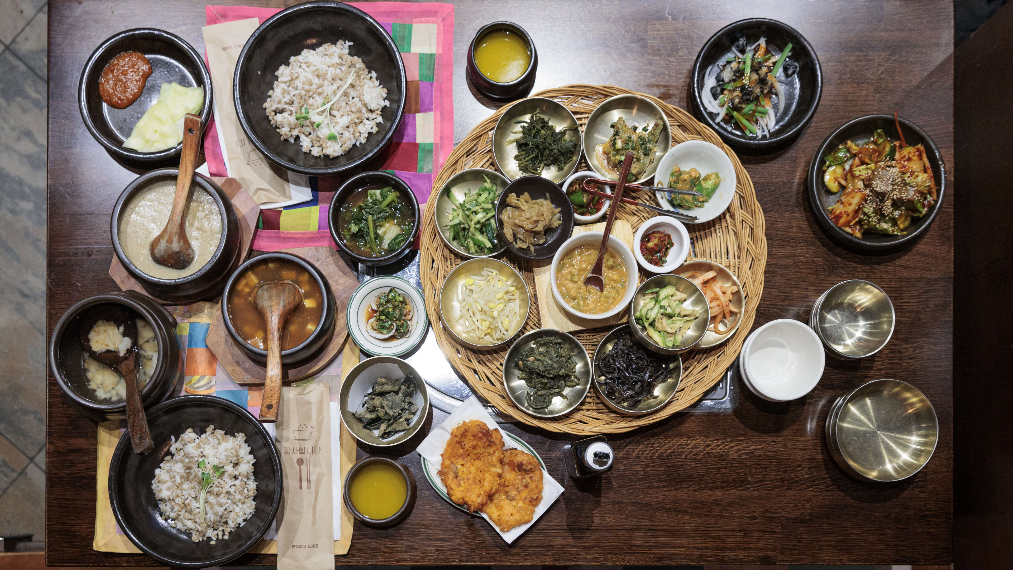 Birdseye view of the full set menu table spread at Borit Gogae. There is a woven basket with sides, bowls of soup and rice and more on the table.