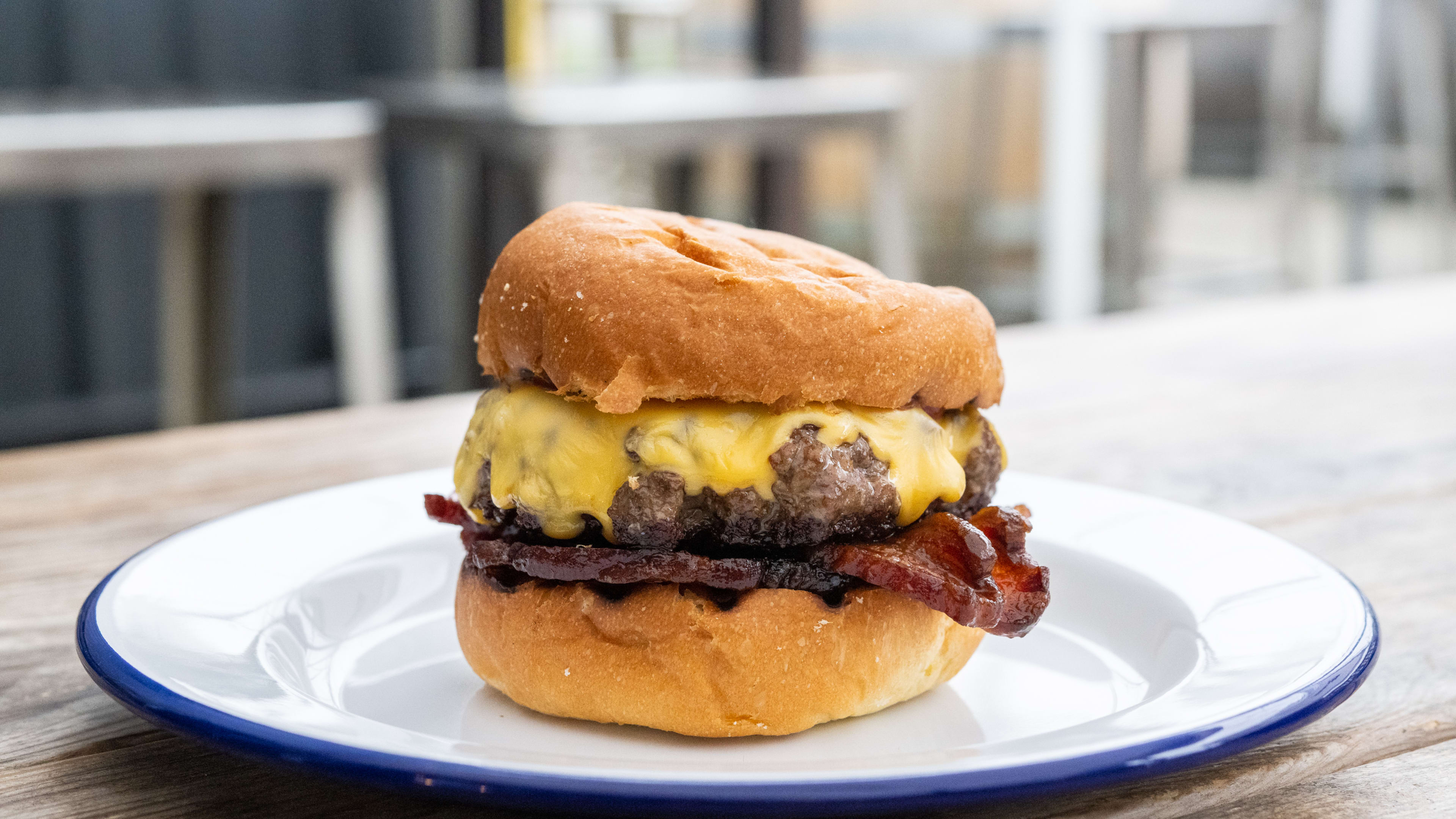 Burger with bacon, a thick patty, and drippy cheese on a plate.