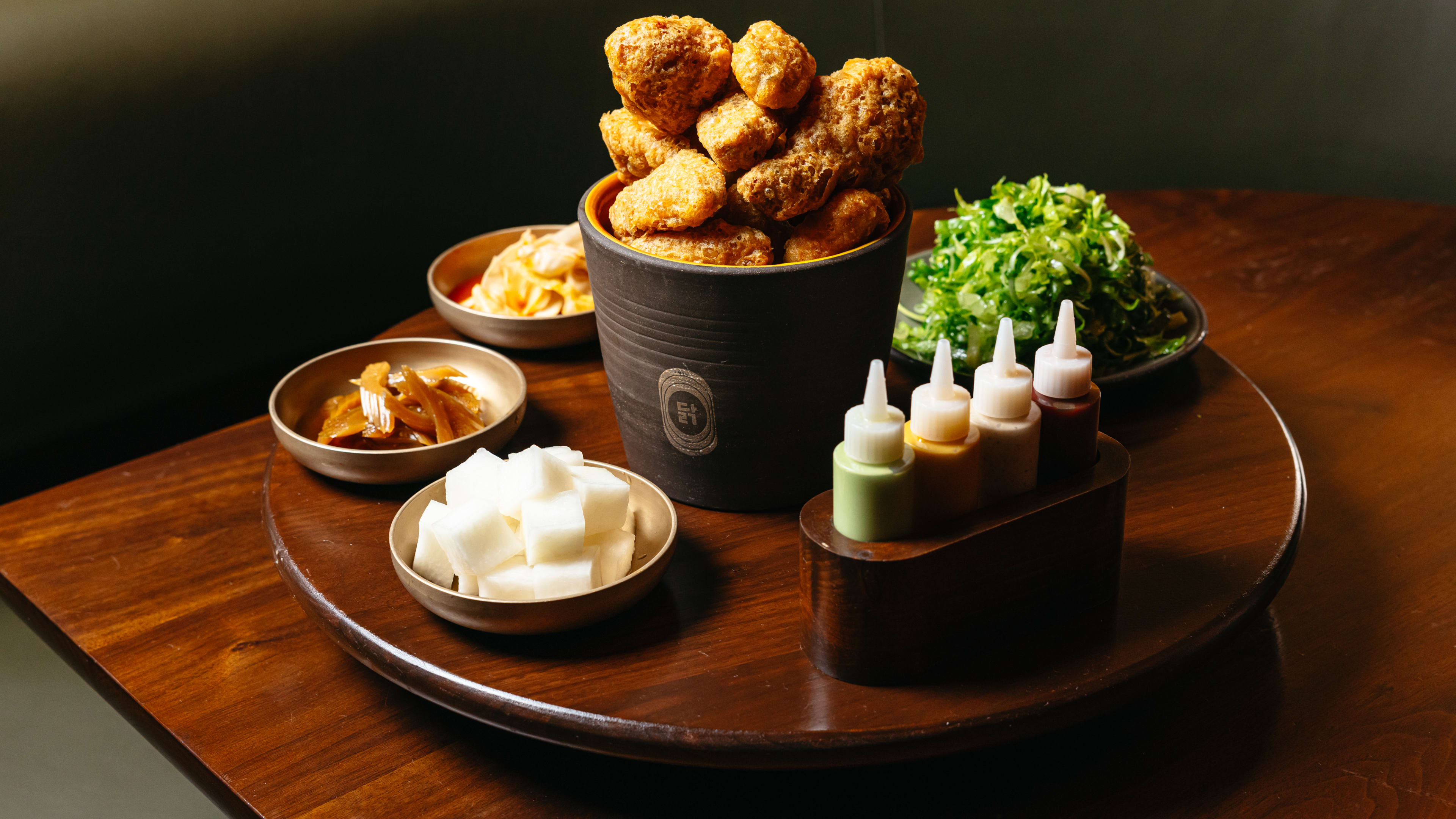 Fried chicken with sauces, banchan, and a cucumber salad.