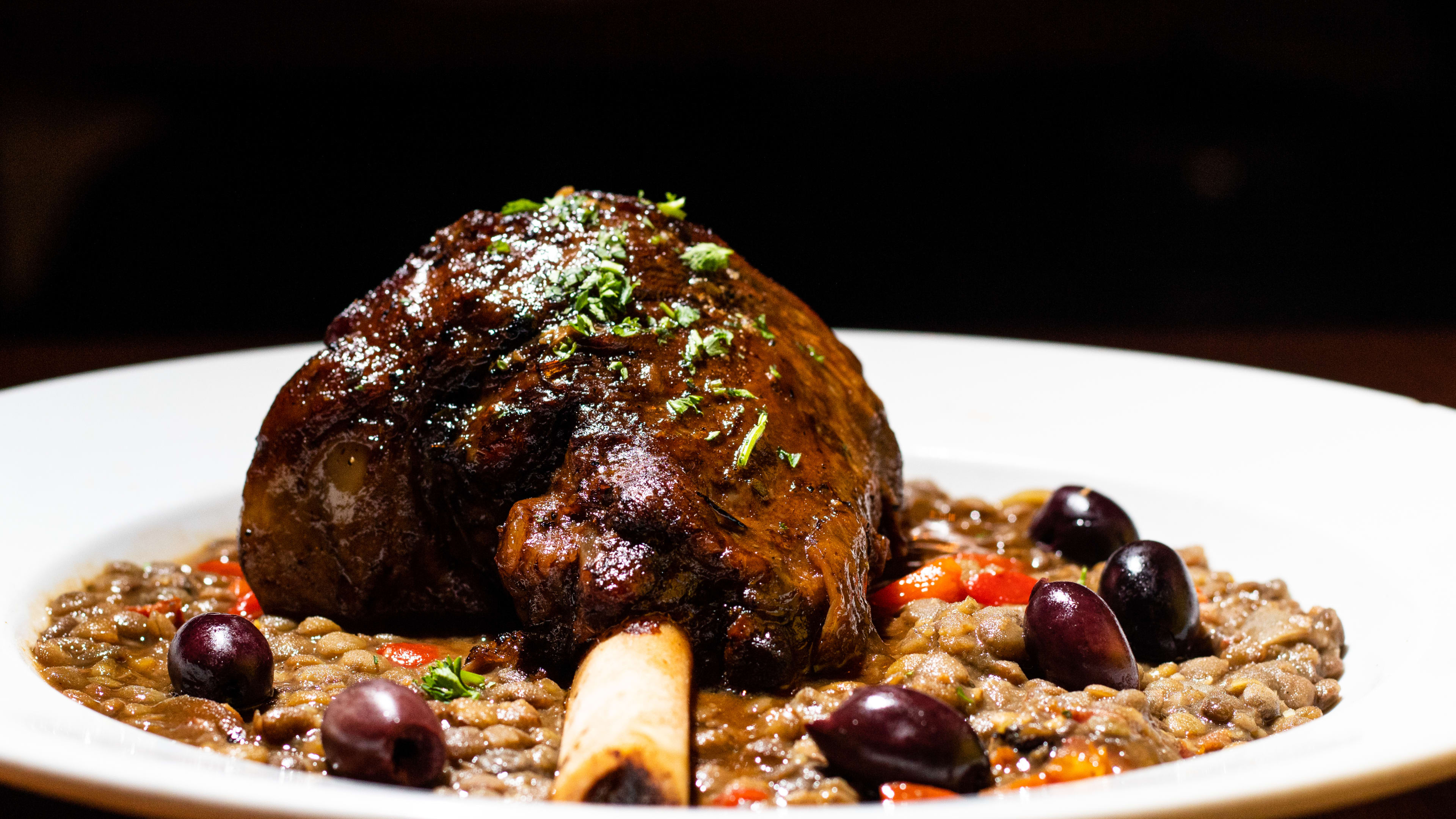 a large piece of lamb with lentils and black olives