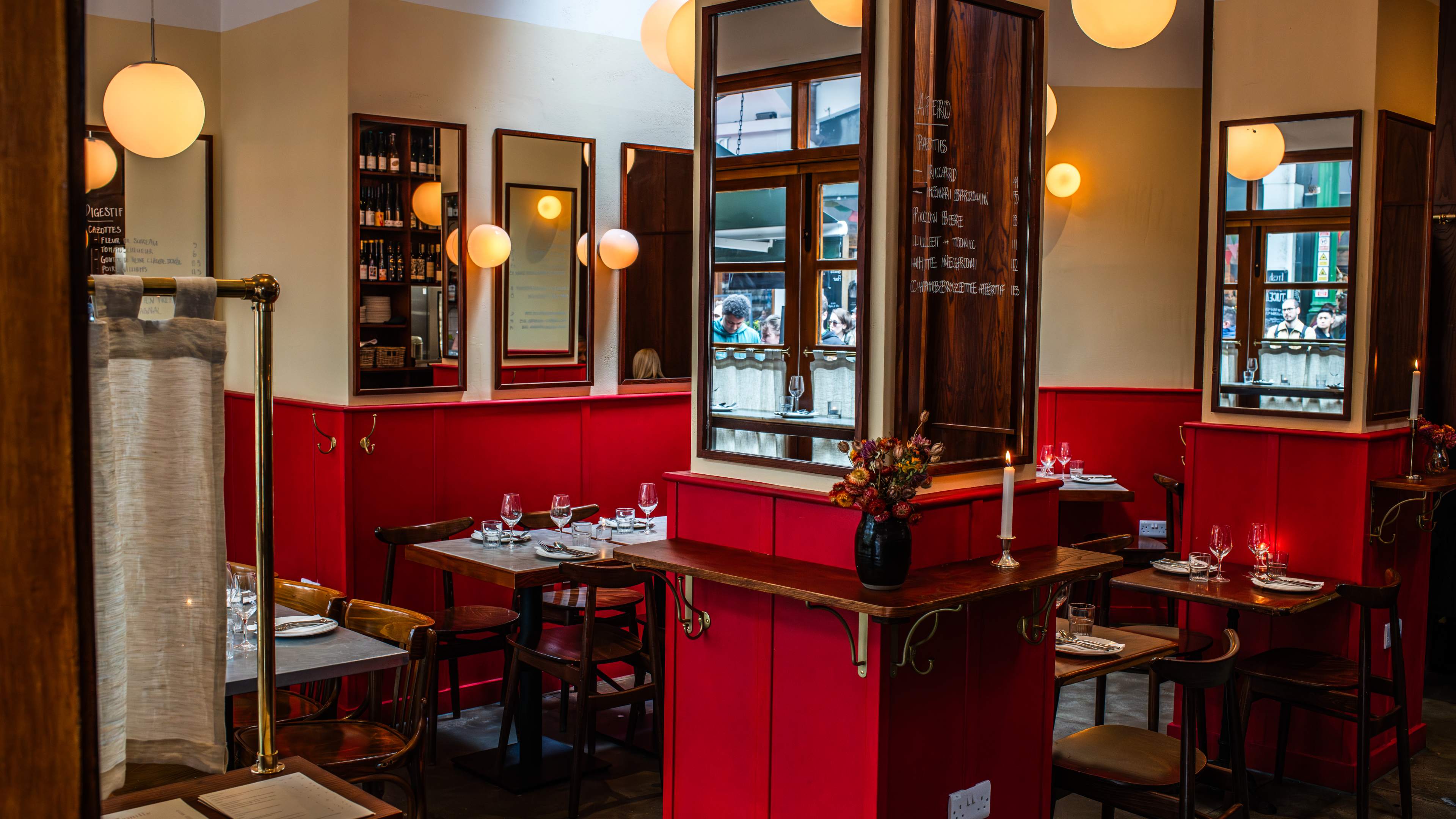 The view as you enter Camille in Borough Market, complete with candles, red hinted walls, and hand written menus on mirrors.