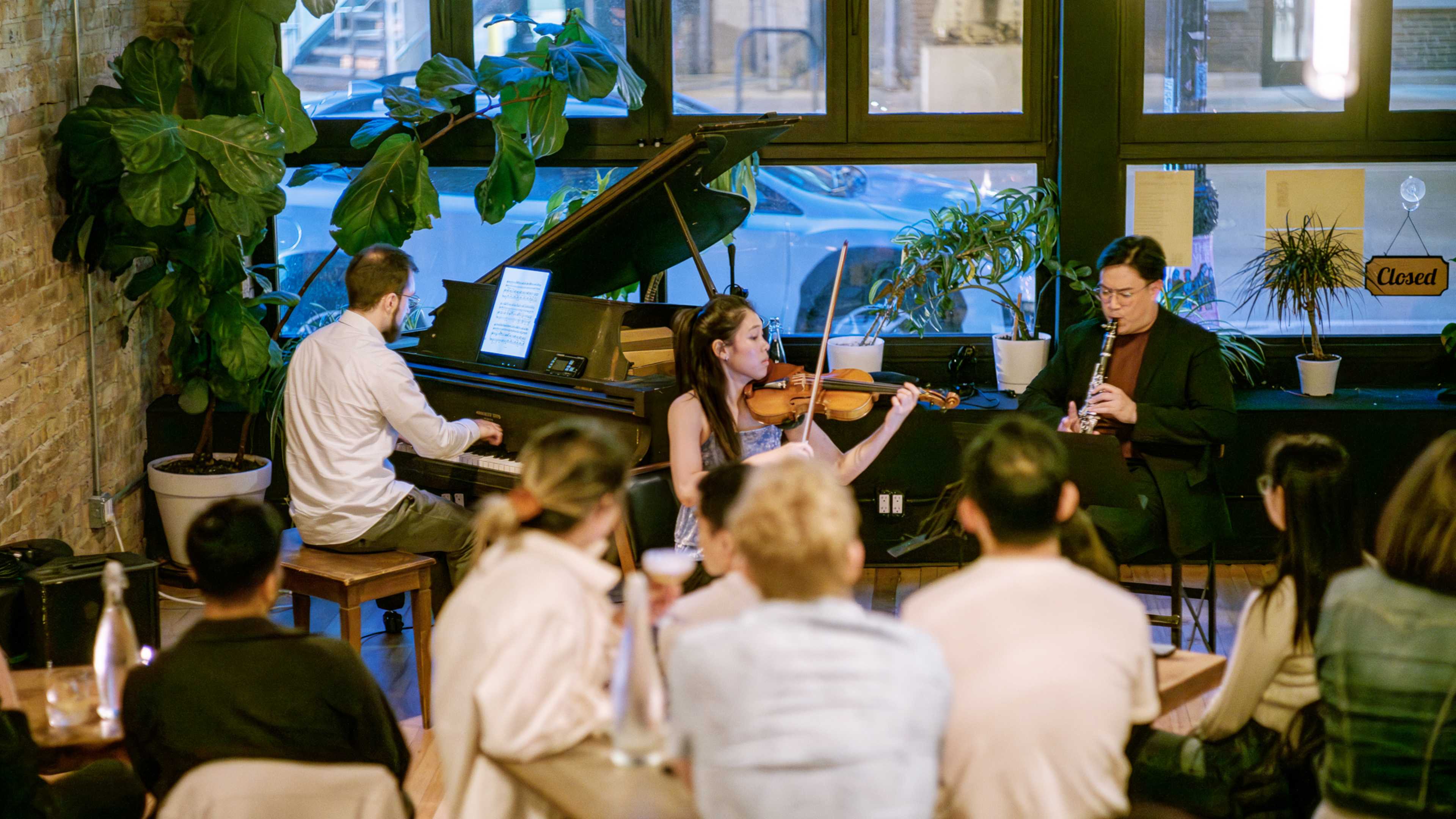 A music trio playing to an audience sitting at tables.