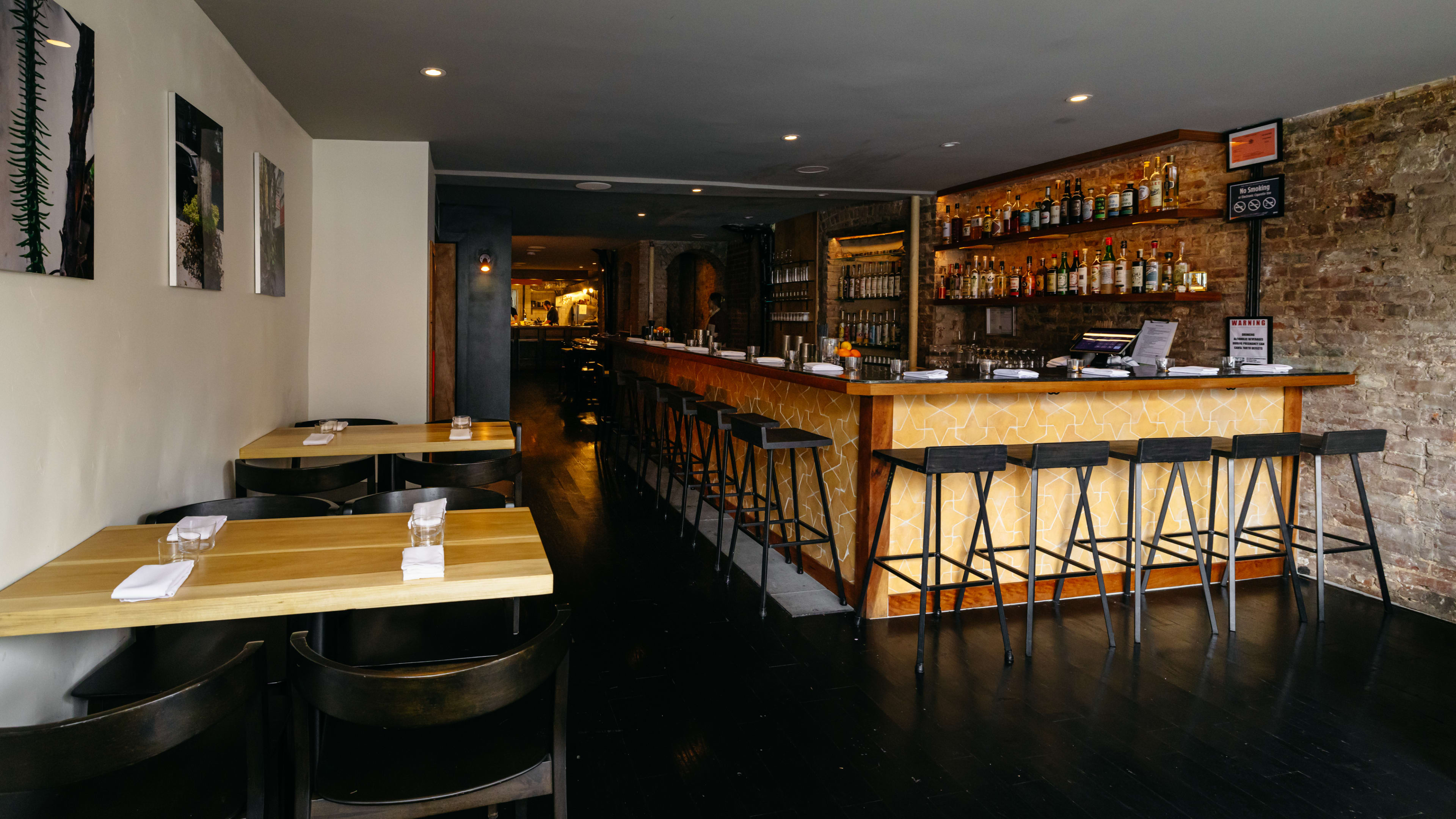 A dining room with a bar on one side and a few tables to the other.