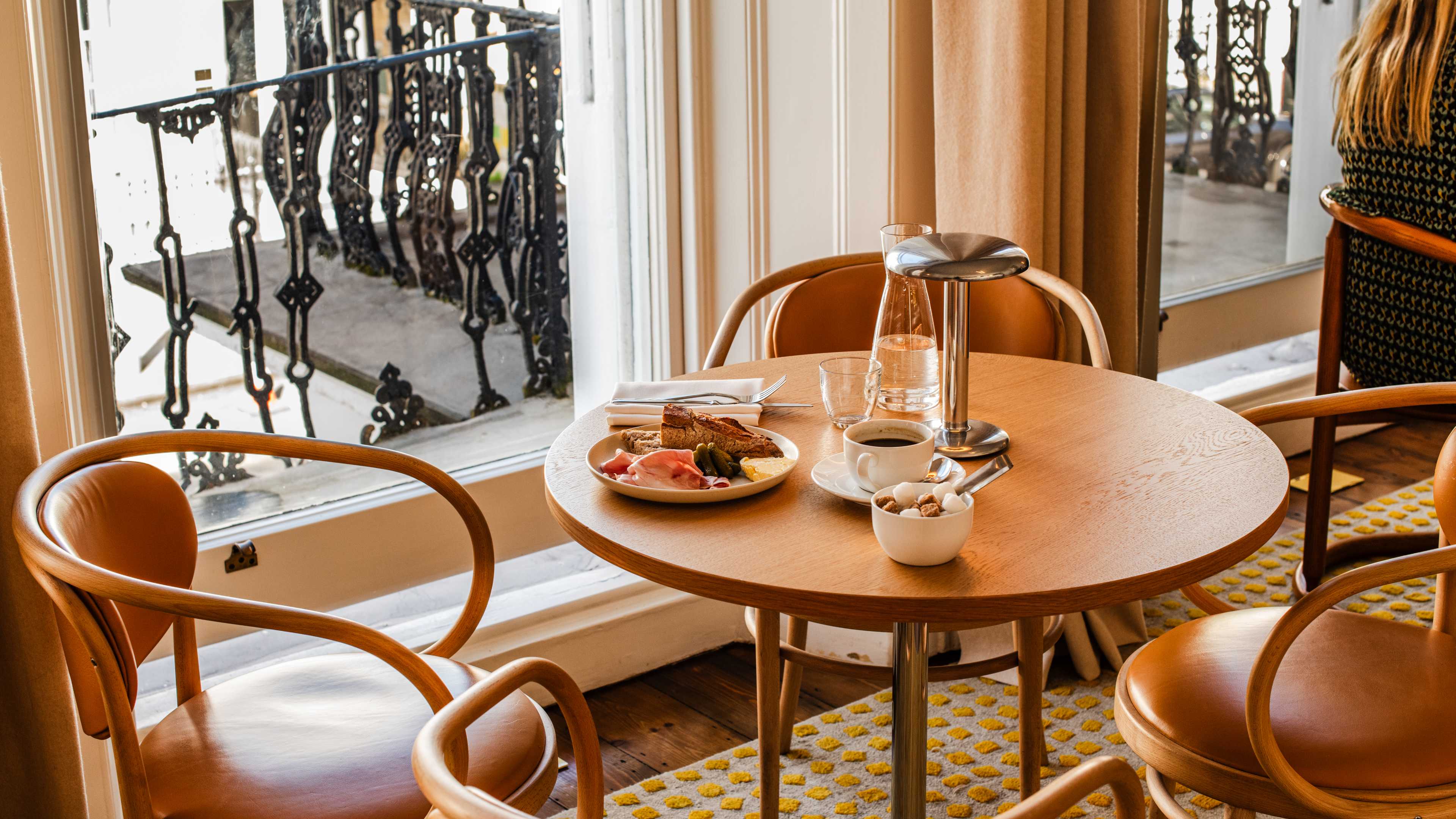 Brown chairs and table with a plate of food and a coffee on it.