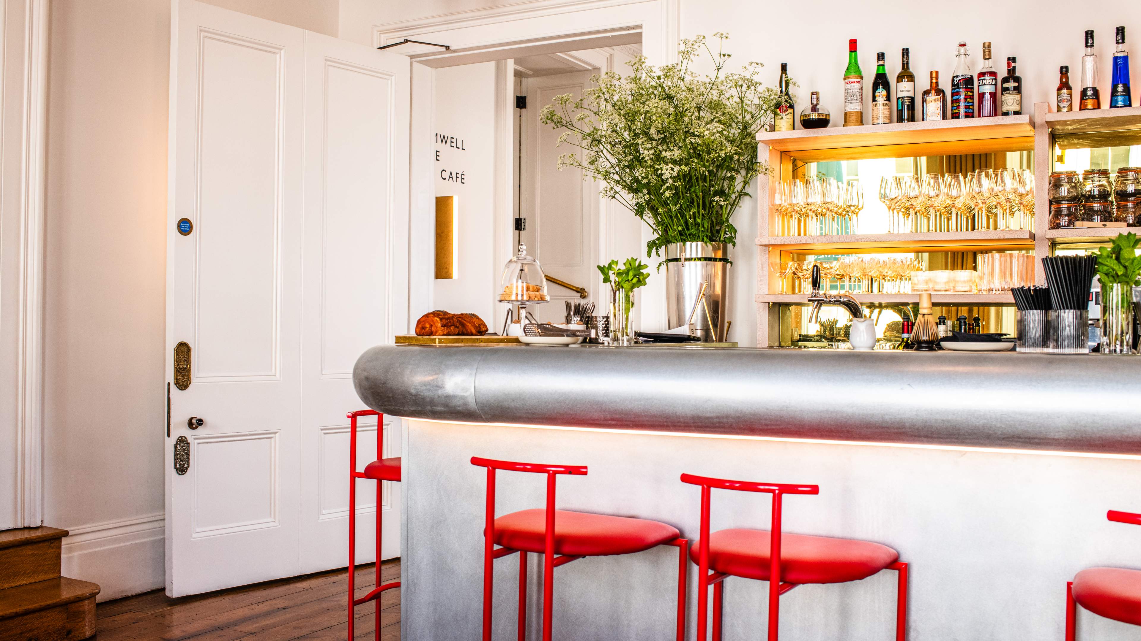 A bright white bar area with red stools.