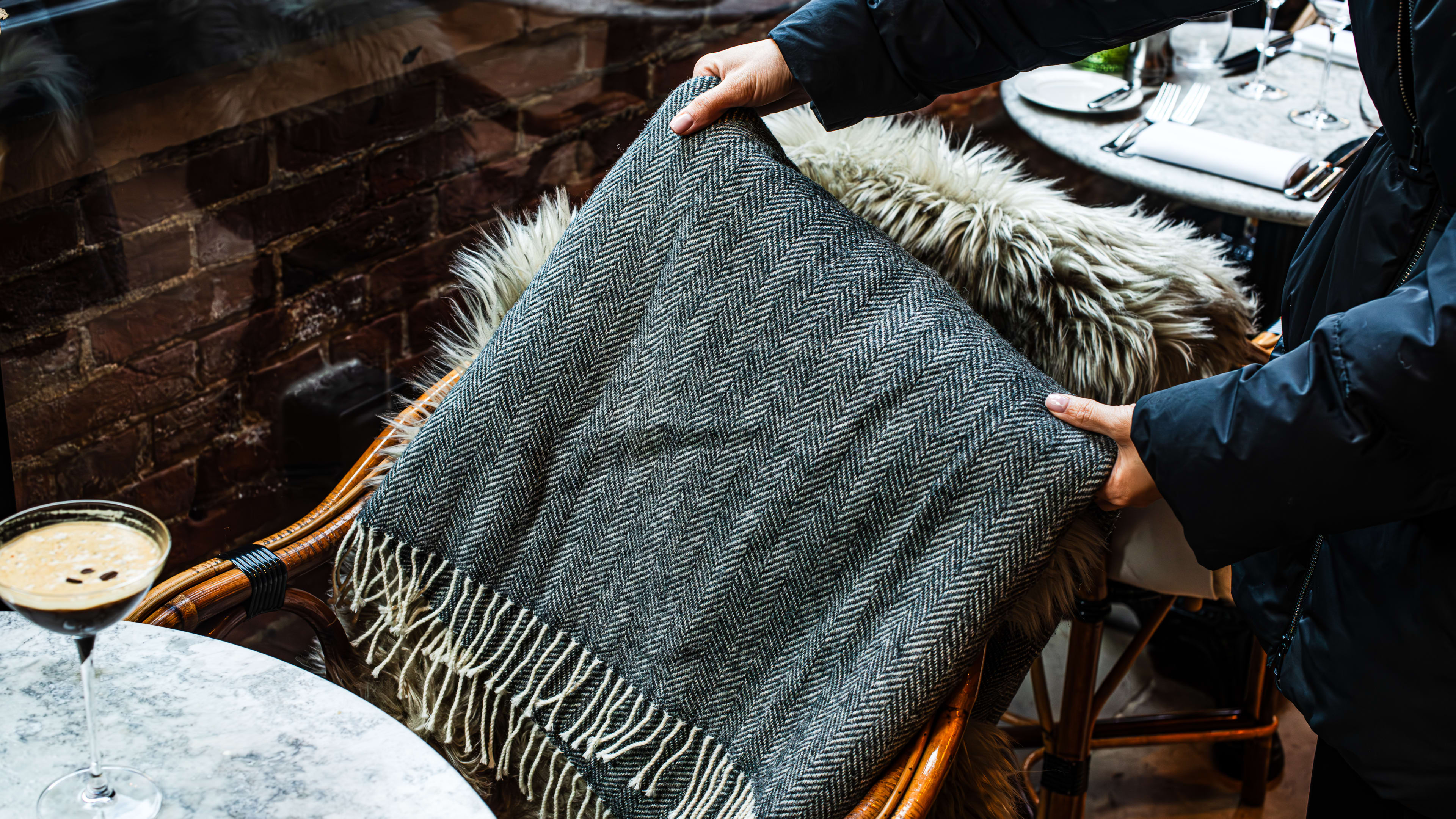 Person placing a blanket on the back of a chair