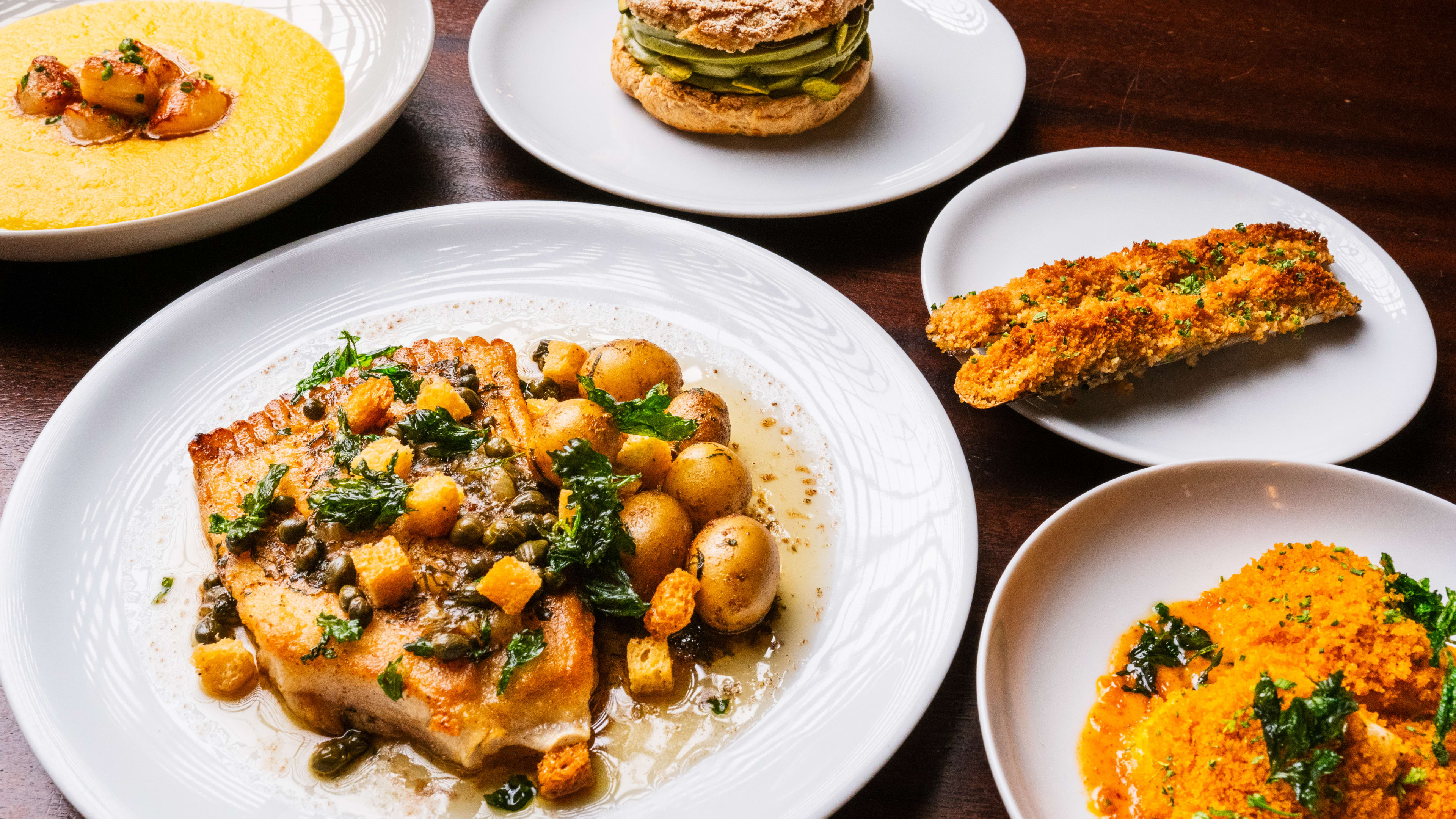 A table covered in French dishes like escargot and skate with potatoes.