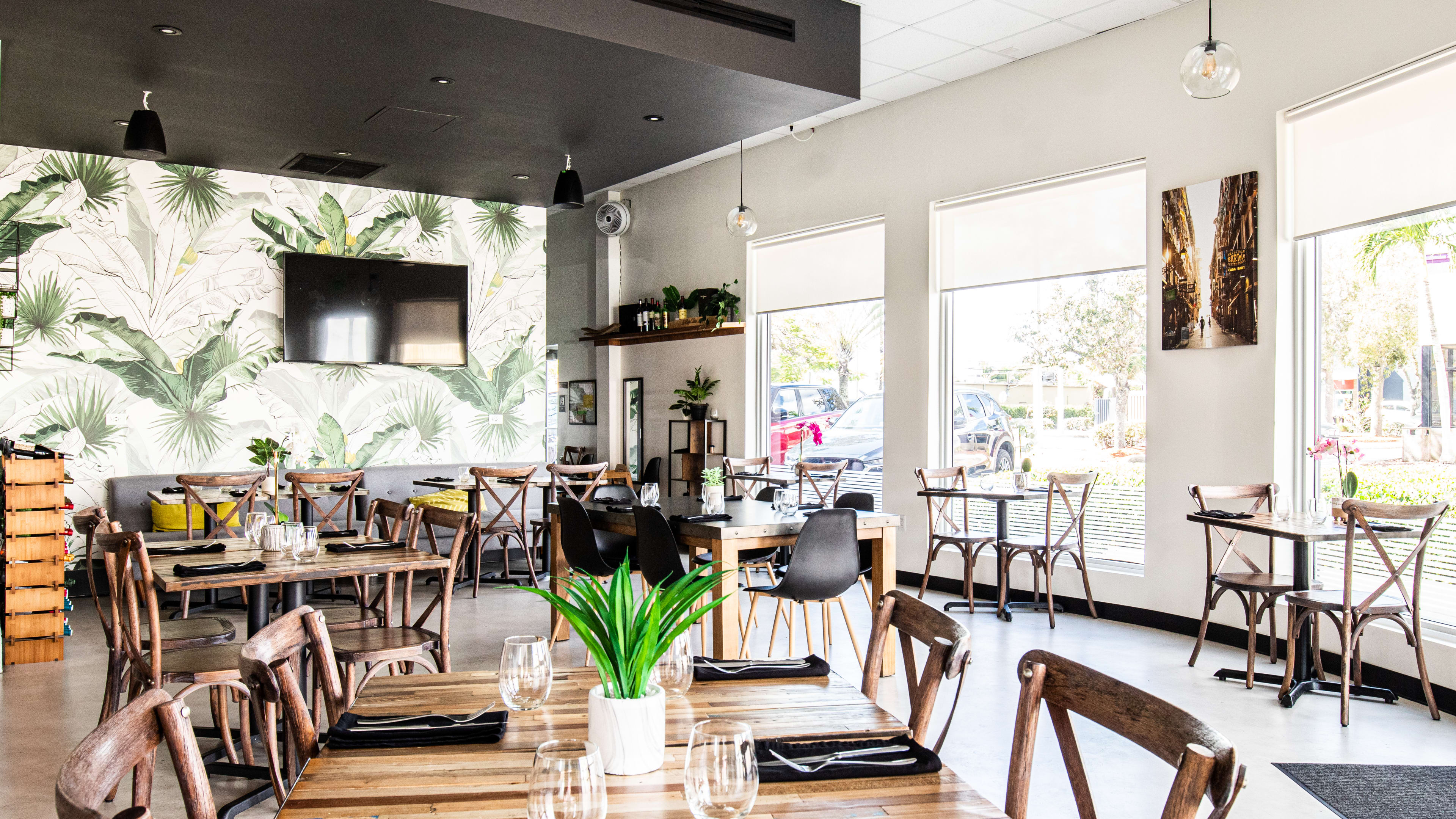 A bright and empty dining room with a dozen tables and big windows.