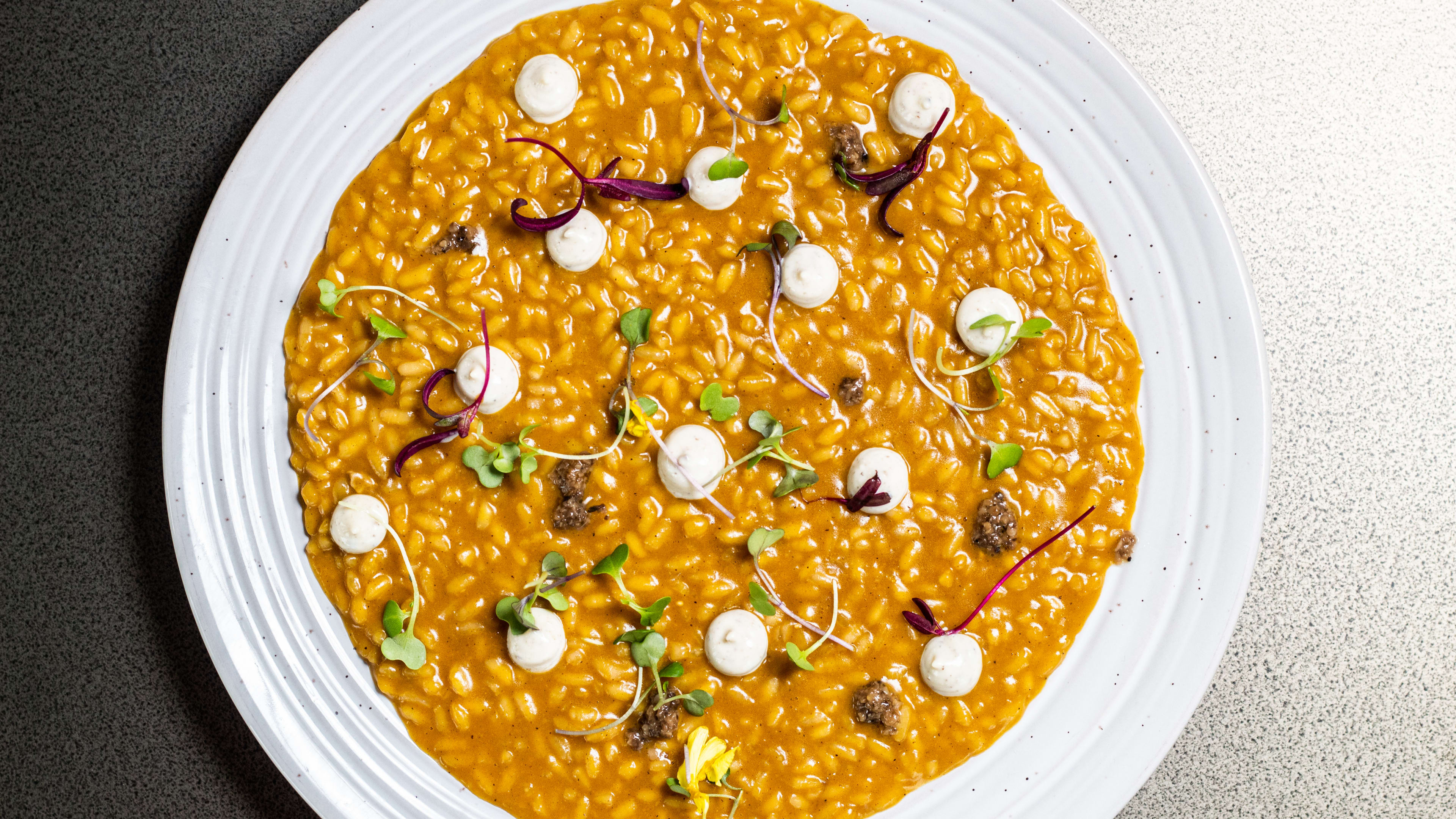 A plate of pumpkin rice with dollops of white sauce.