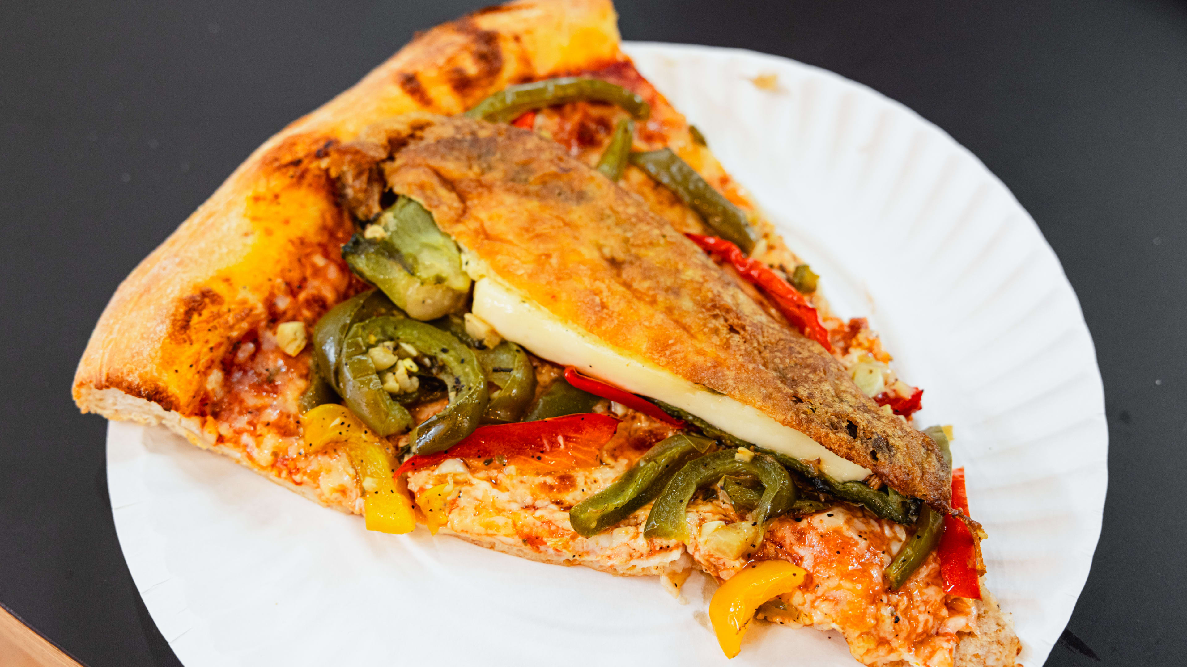 A slice of pizza with a chile relleno on top.