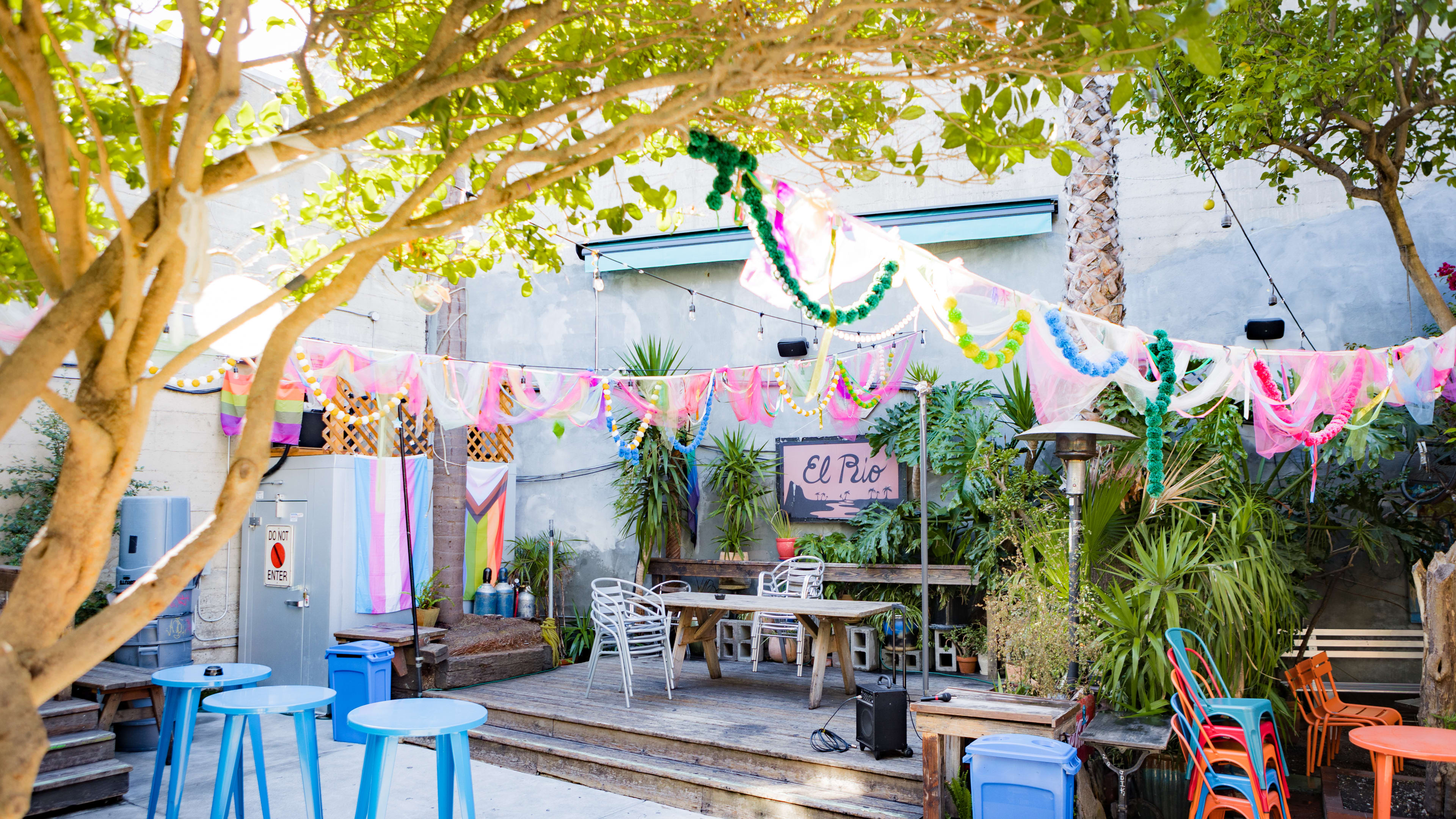 The patio at El Rio with seats, LGBTQ+ flags, and pom poms overhead