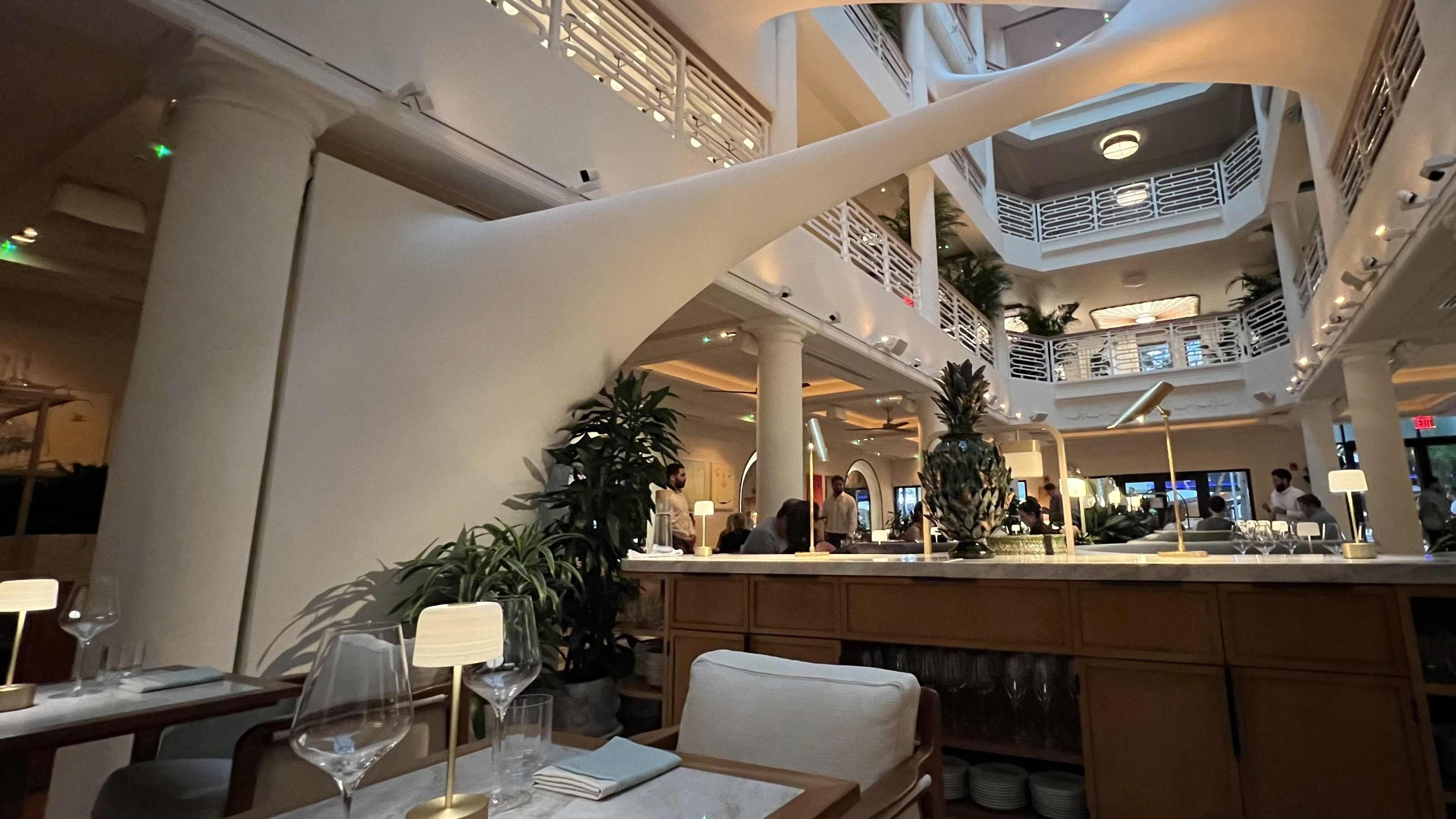 A big dining room with tall ceilings and a unique installation overhead.