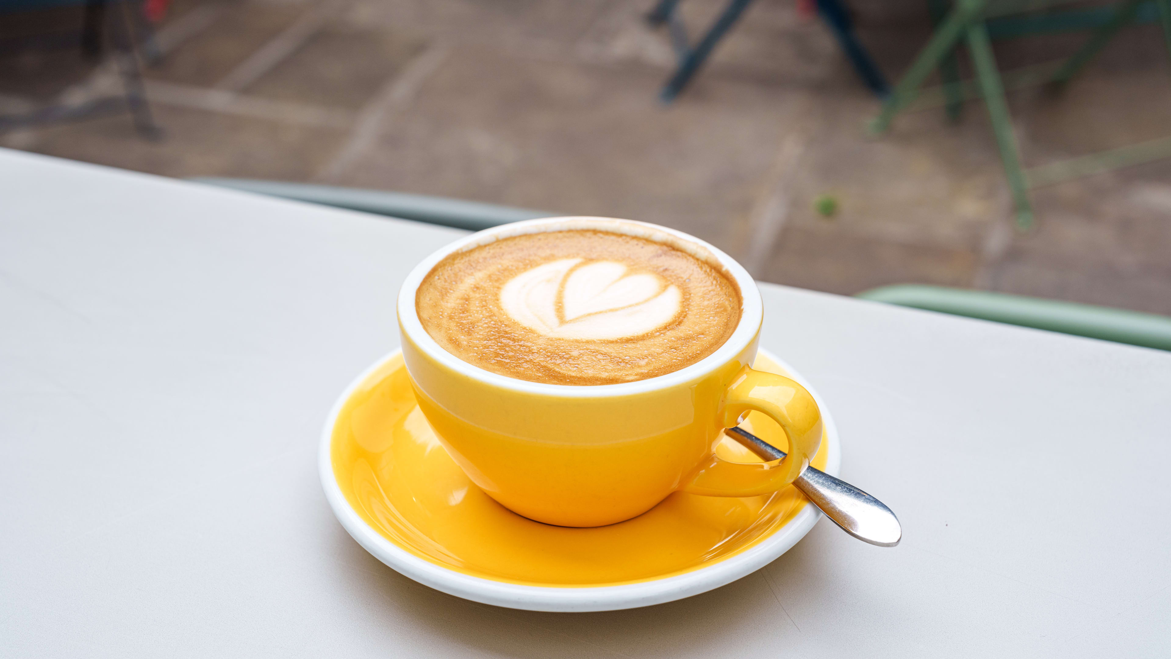 A latte in a yellow mug.