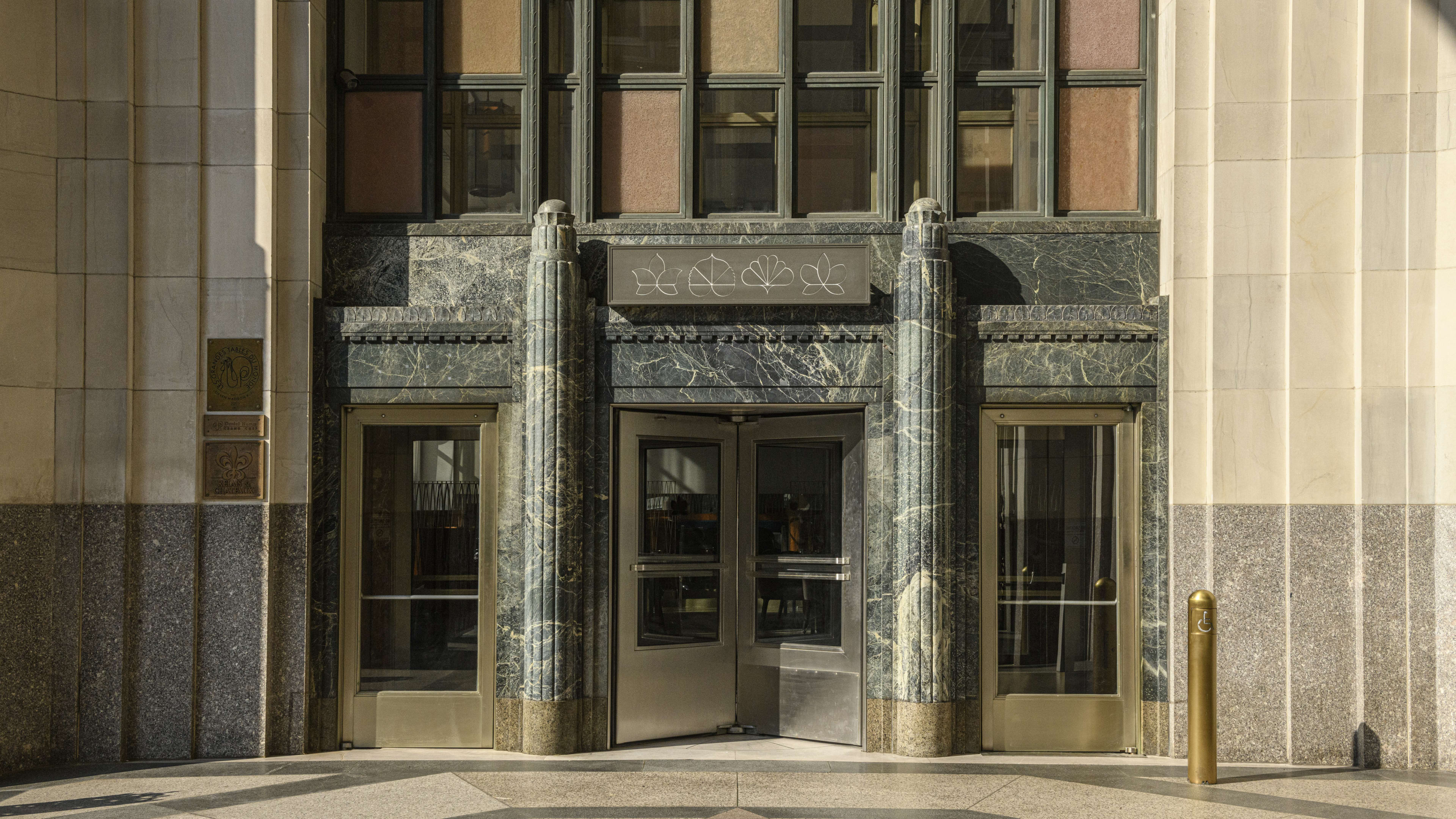 The outside of Eleven Madison Park, with a revolving door surrounded by a marble facade.