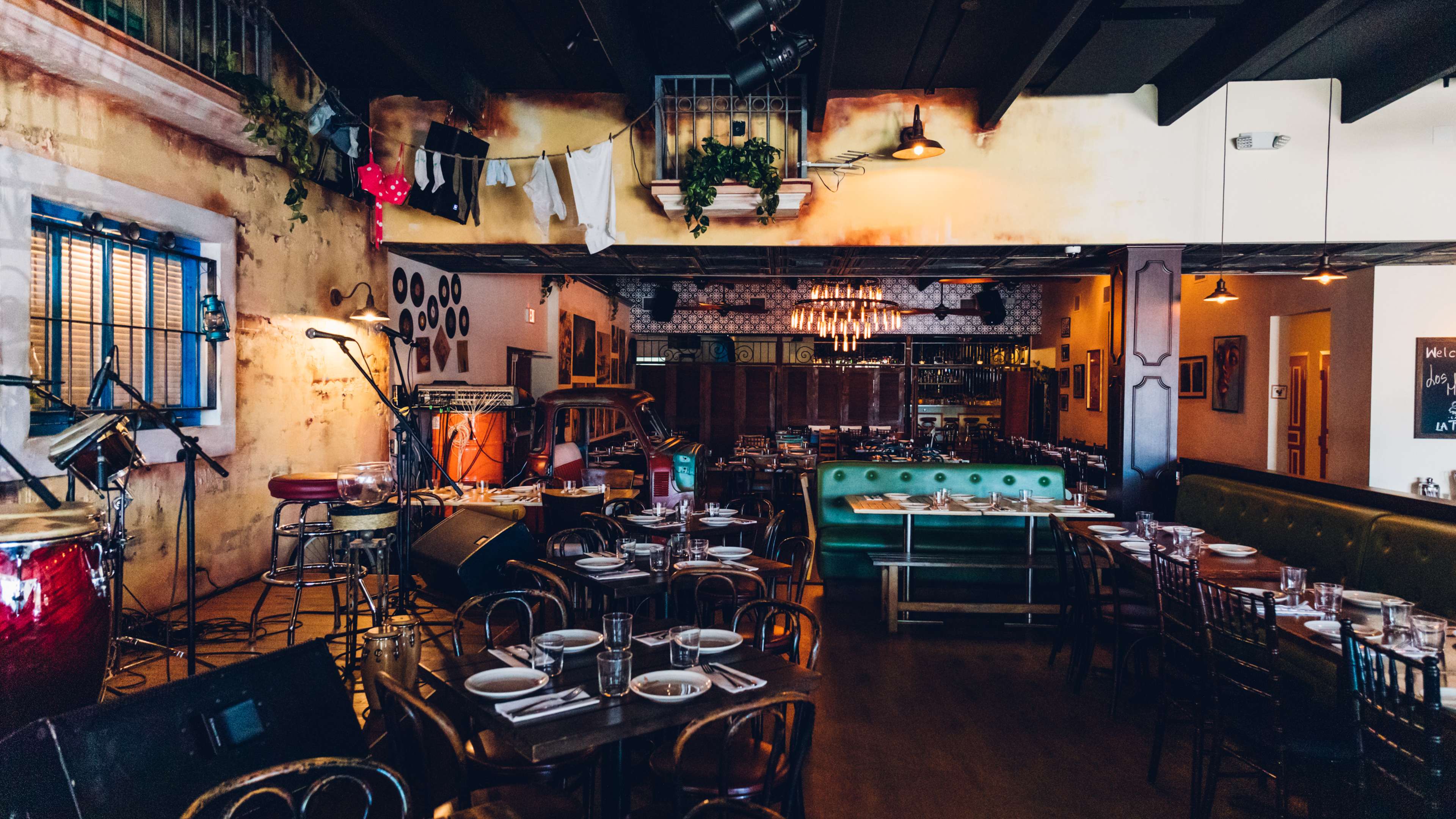 Restaurant interior with stage filled with instruments and rustic looking walls with vines.