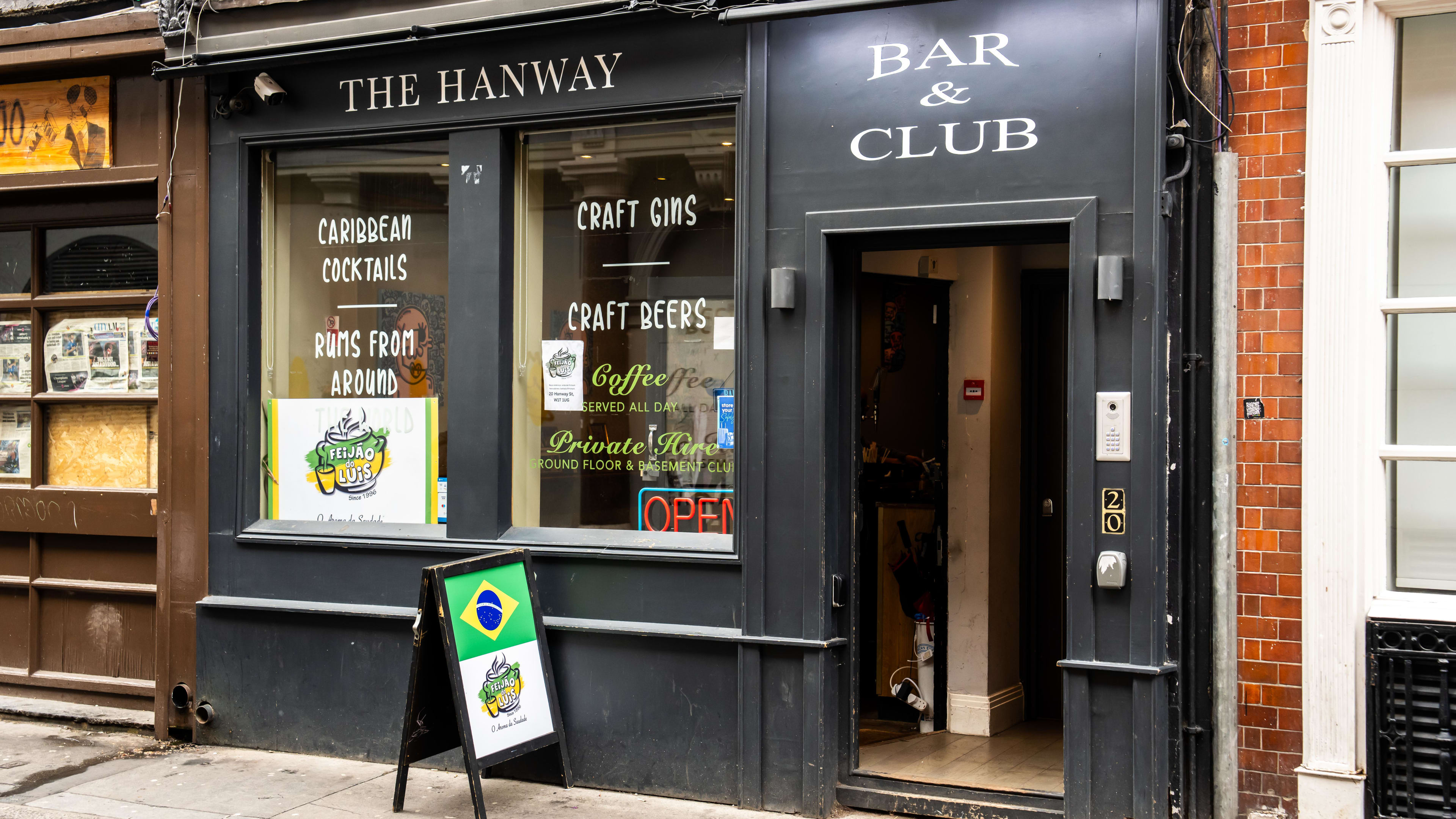 Black exterior of a pub called The Hanway, with sign in the window for Feijão Do Luis.