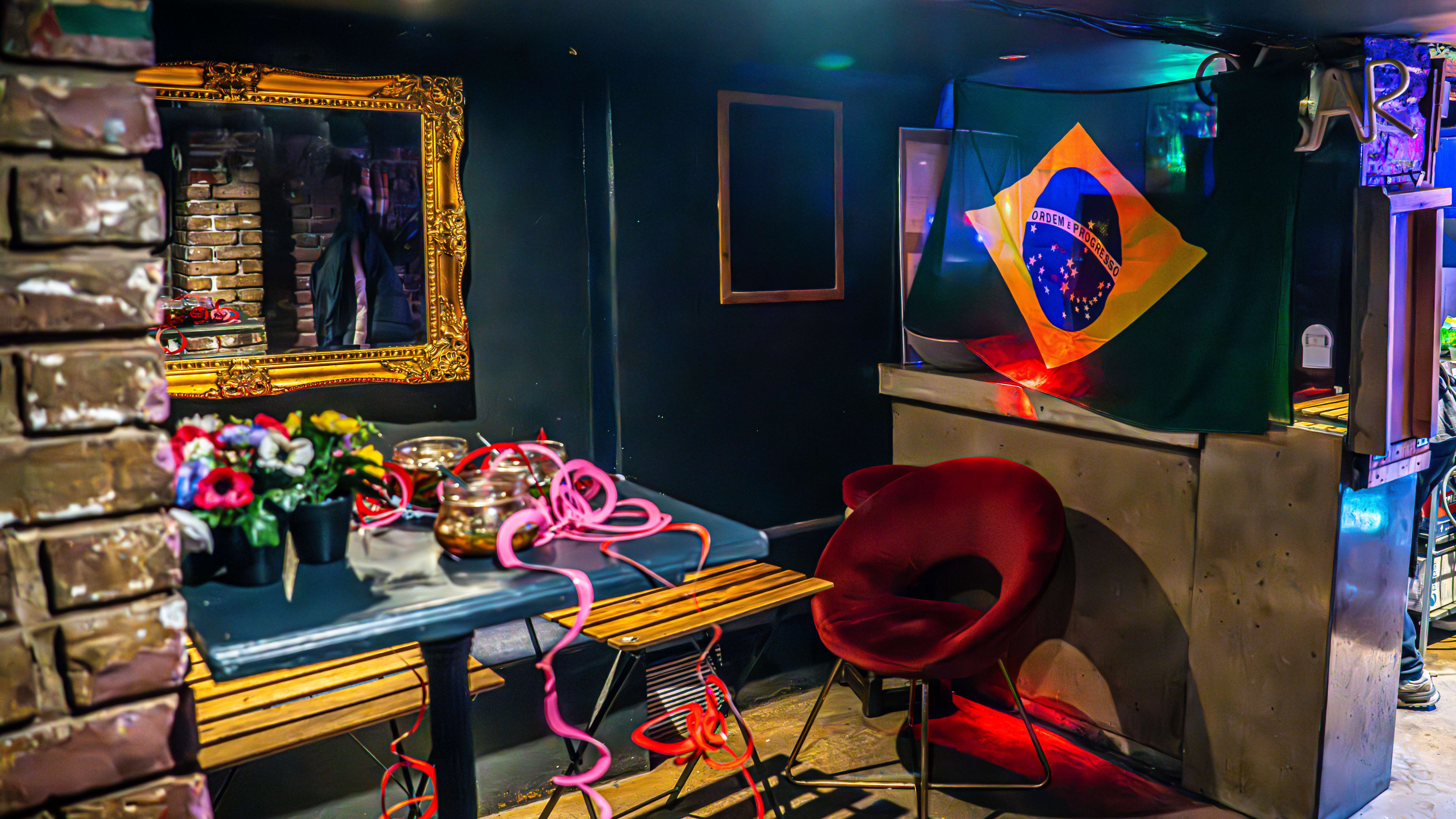 Restaurant interior with a Brazilian flag, dark blue walls, and red velvet seats.