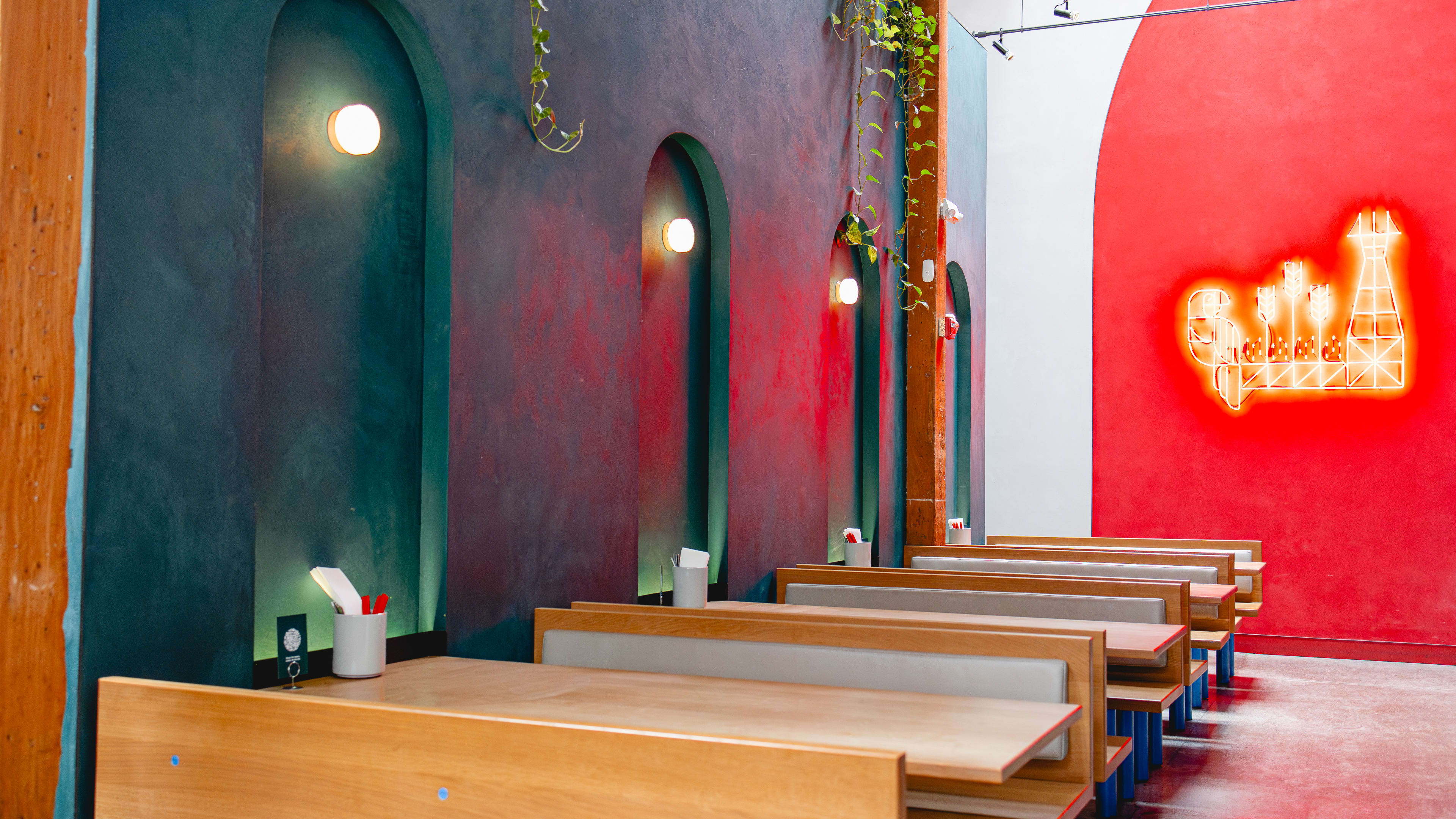 interior with booths, colorfully painted wall, and neon light