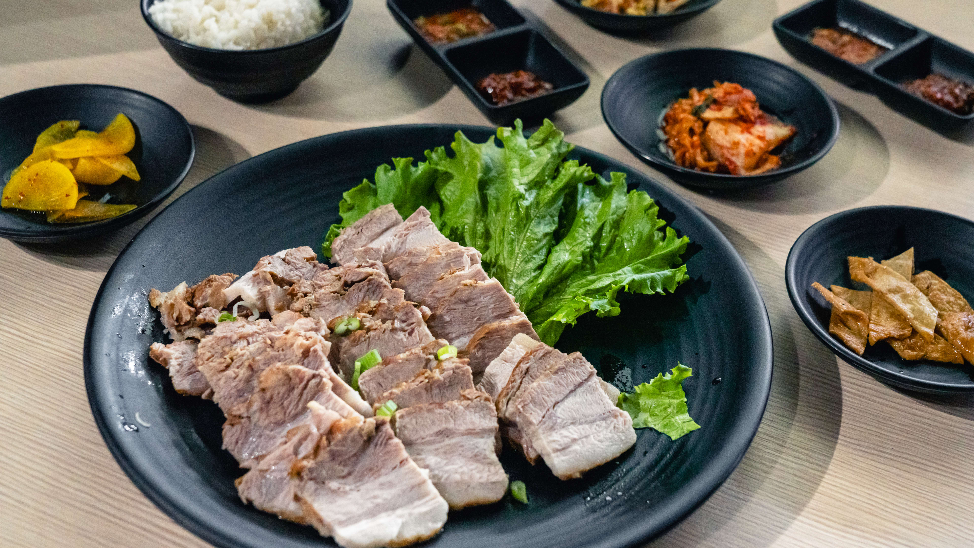 Spread of Korean dishes such as sliced meat, kimchi, rice, ginger and other banchan.