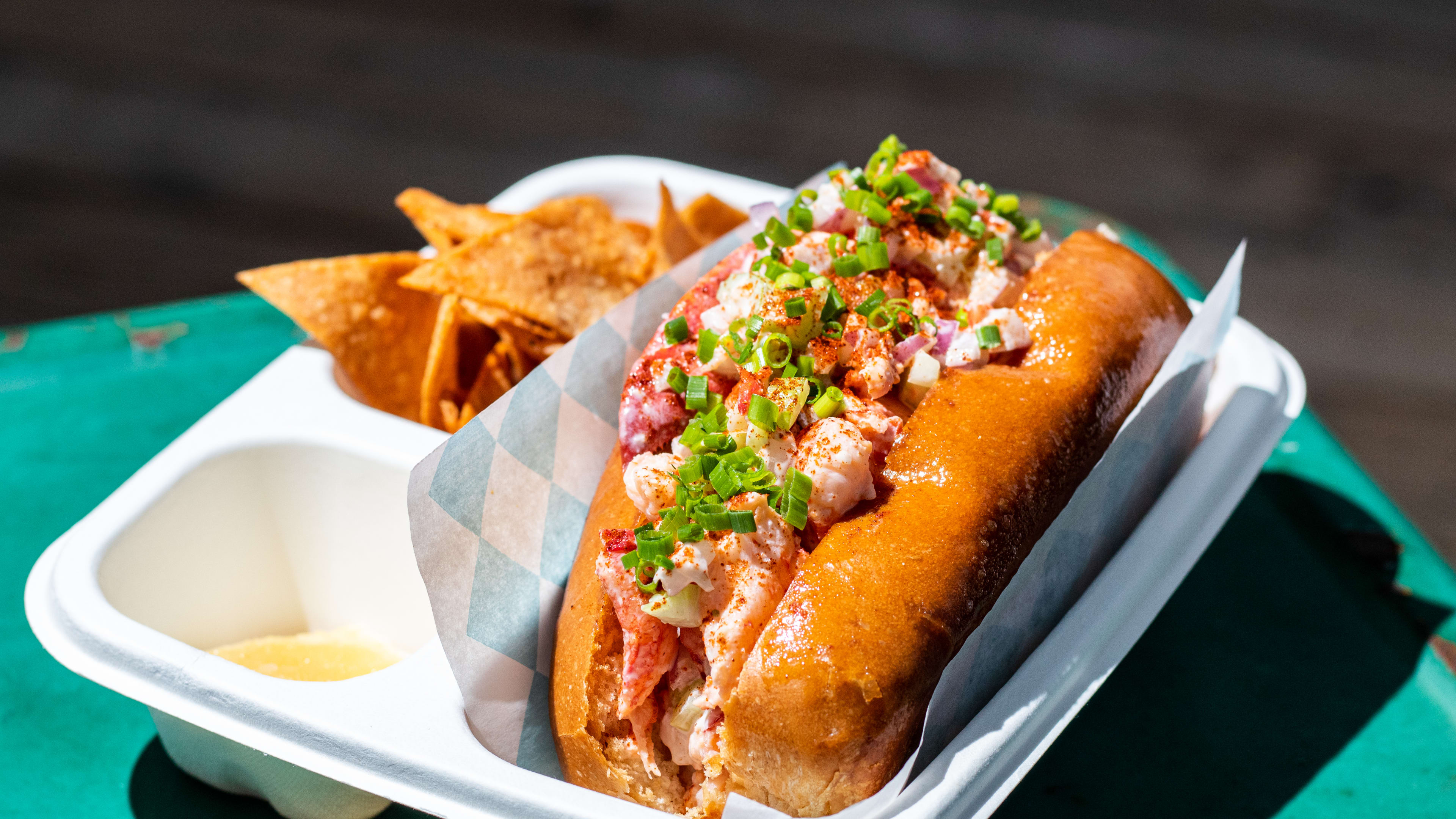 A lobster roll with a side of chips.