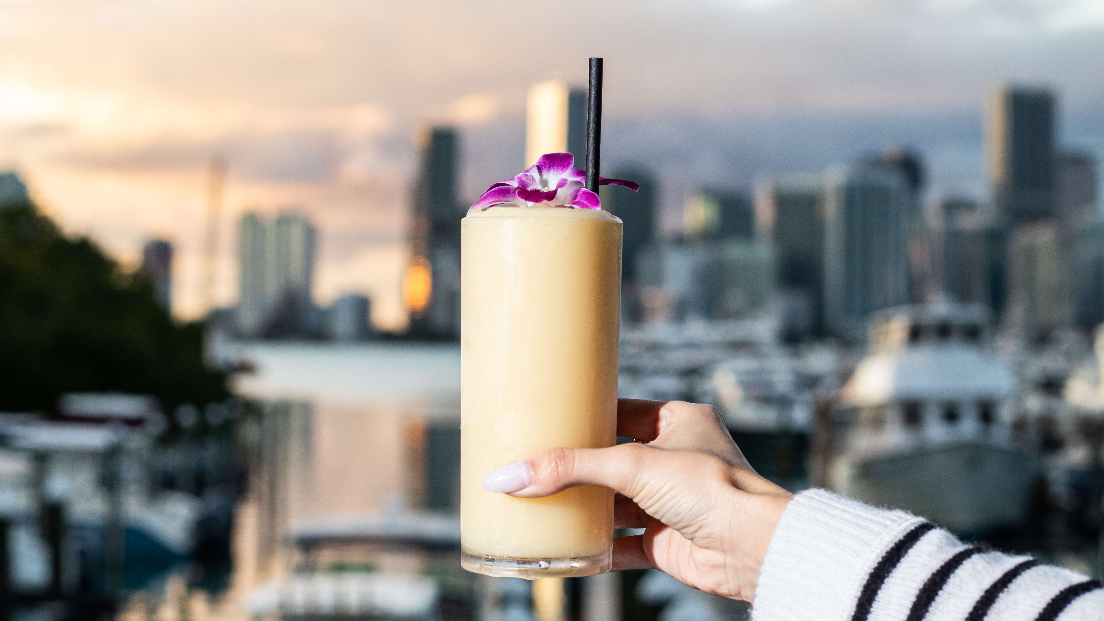 A cocktail held up against a waterfront background.