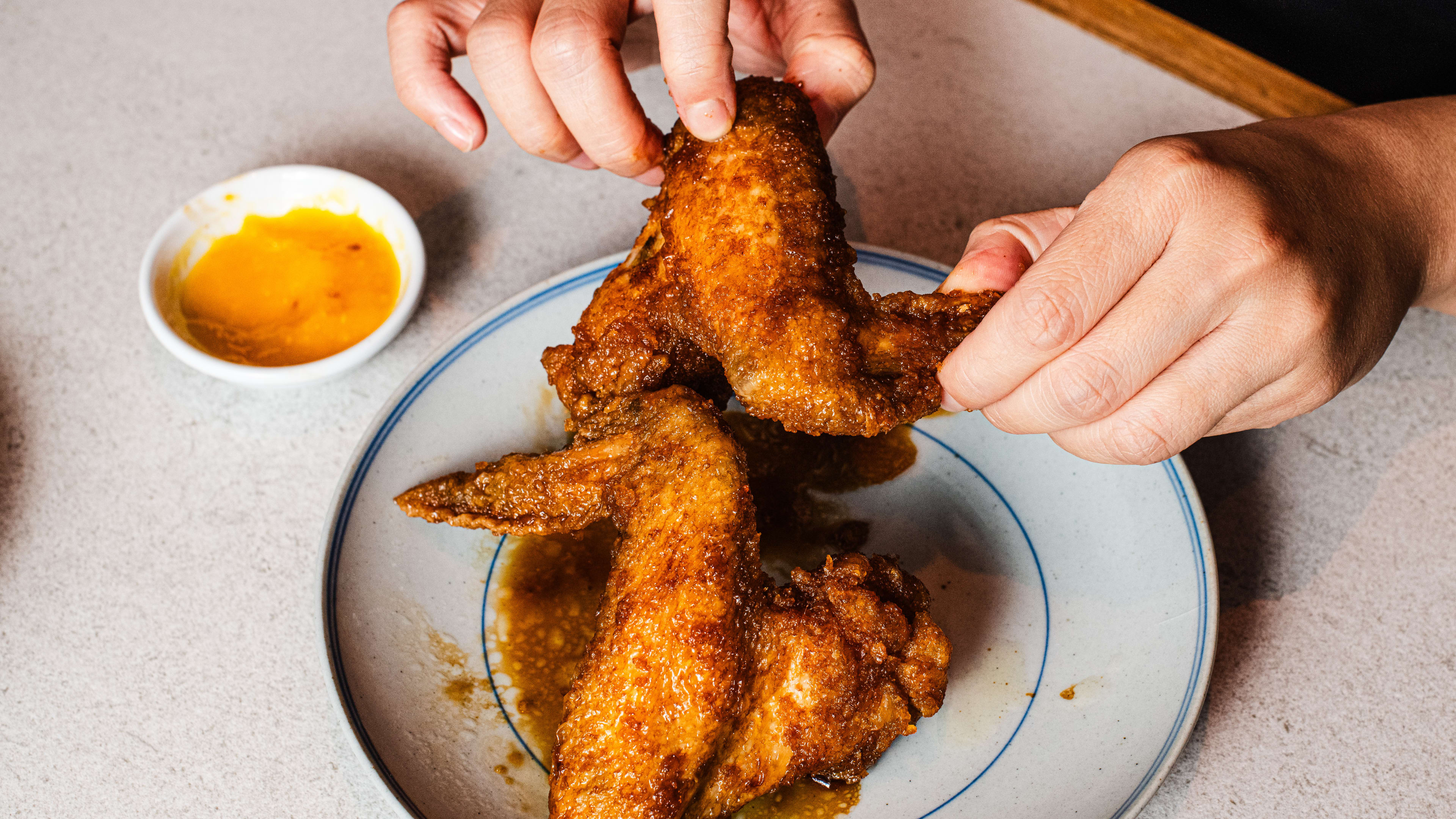 Person picking up a Cola Wing from a plate.