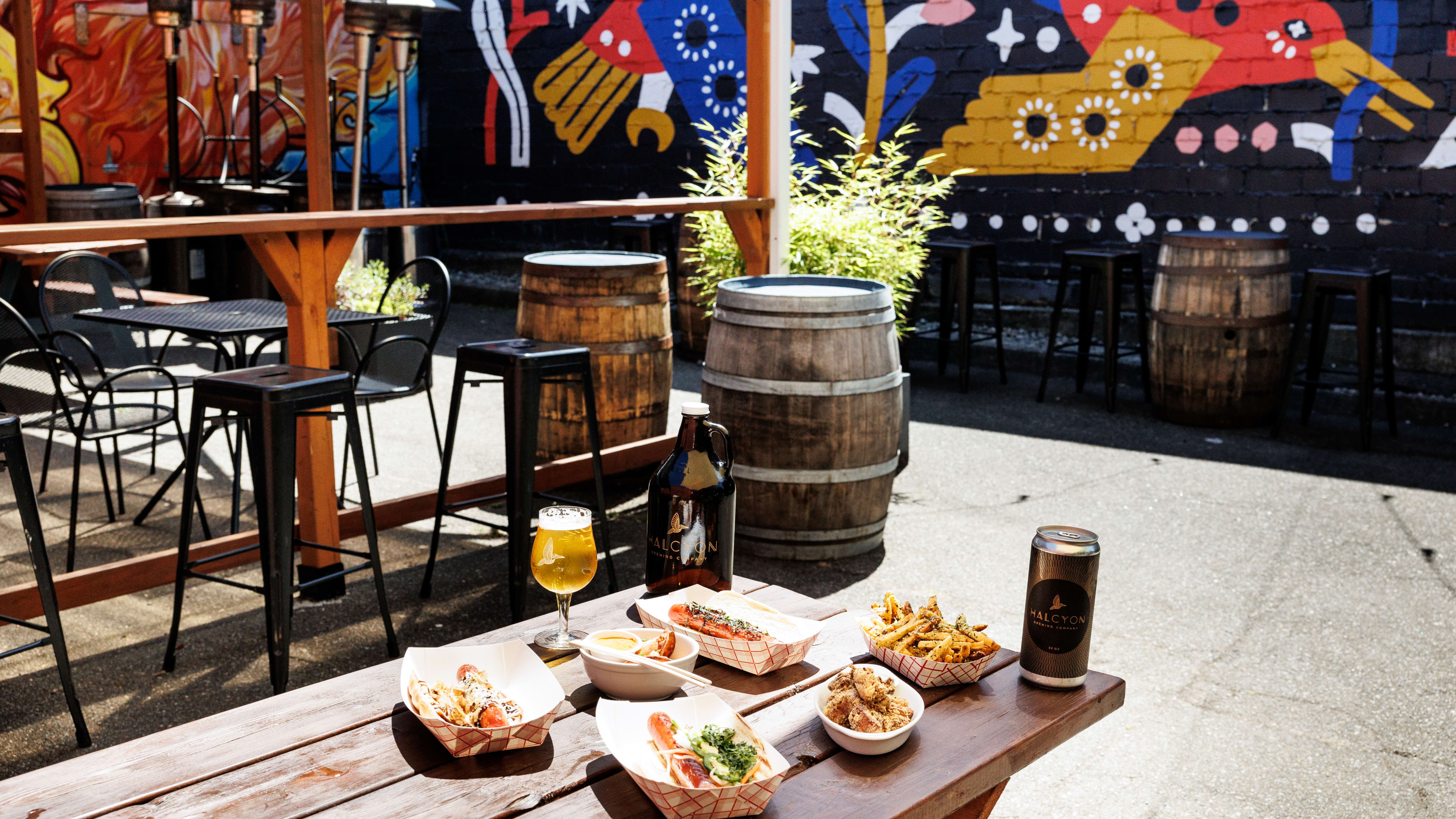 brewery patio with spread of beers and food looking out onto mural