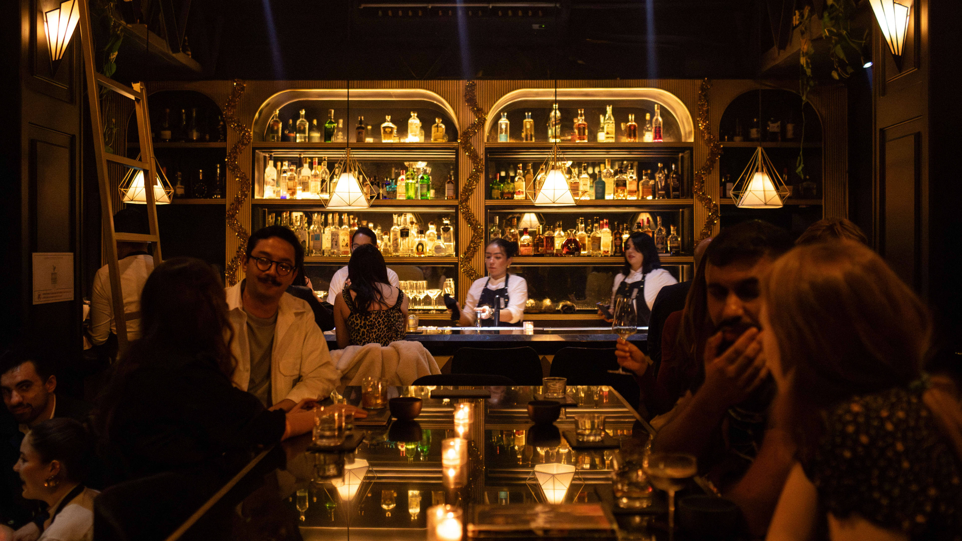 People standing around a communal table at Handshake, a speakeasy in Mexico City