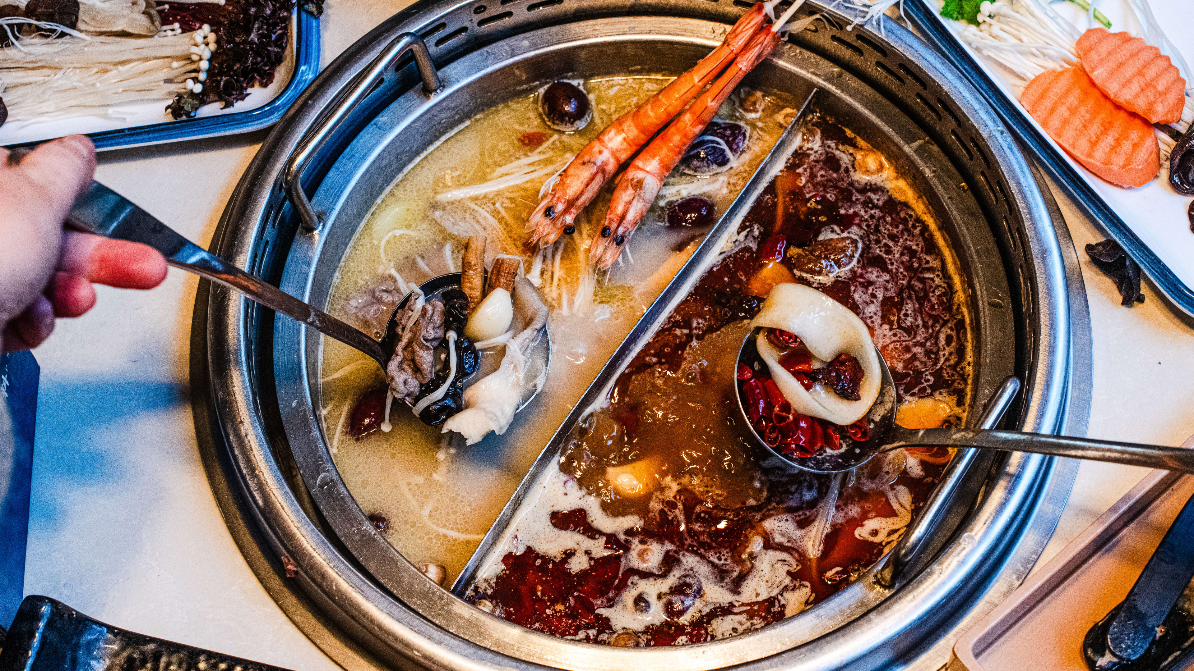 dual flavour hot pot with nourishing marrow chicken broth and spicy marrow chicken broth. Cooking beef and lamb, king prawns, fish balls, mushrooms, vegetables and noodles.