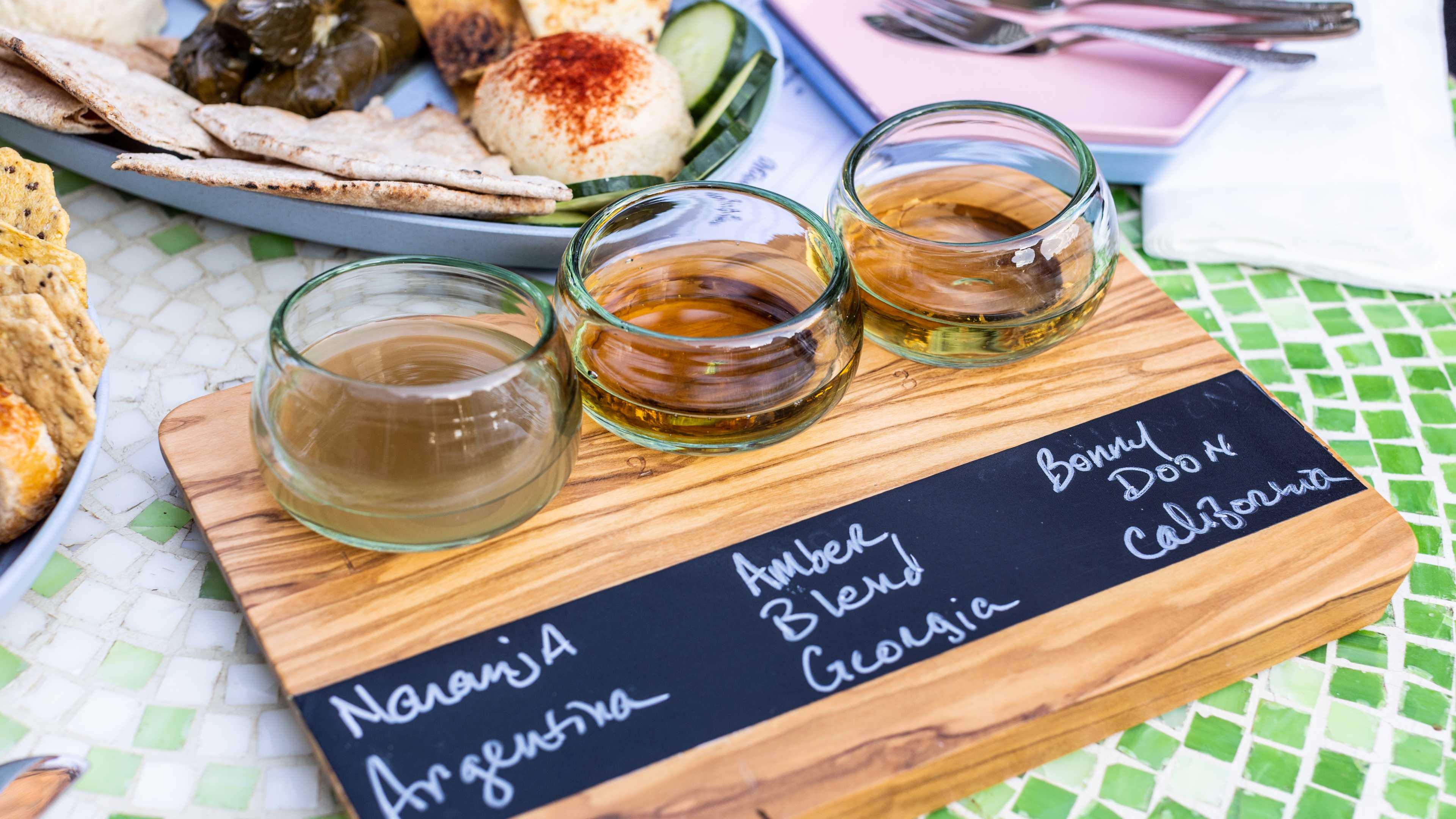 The Orange Wine Flight served on a wooden holding tray with the wine types written on a chalkboard section of the tray.