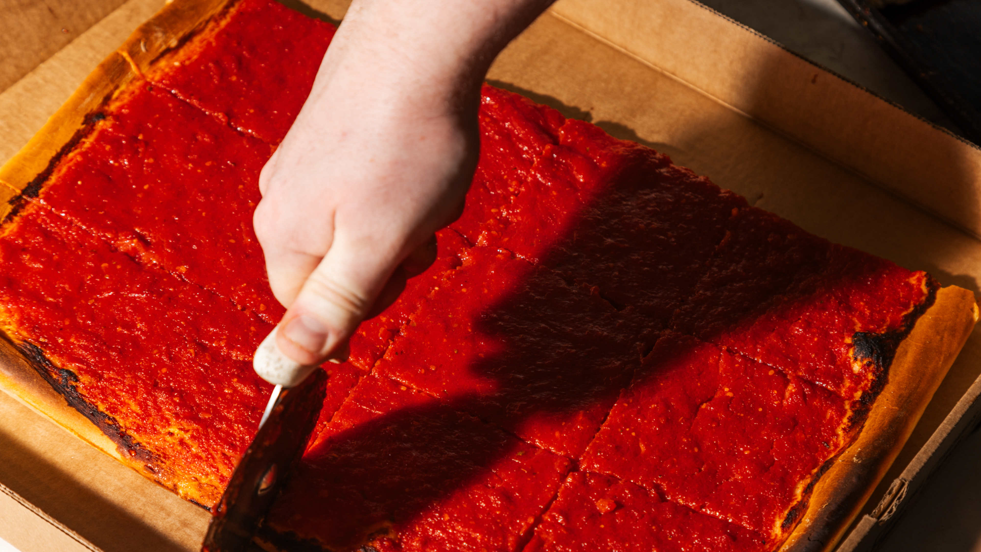 a person slicing into a rectangular tomato pie