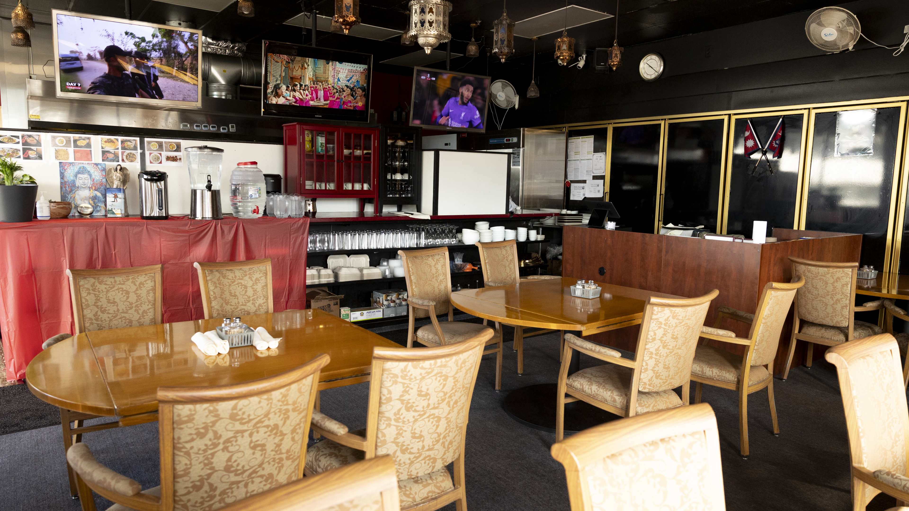 Dining room with wooden tables, black walls, and lanterns hanging from the ceiling