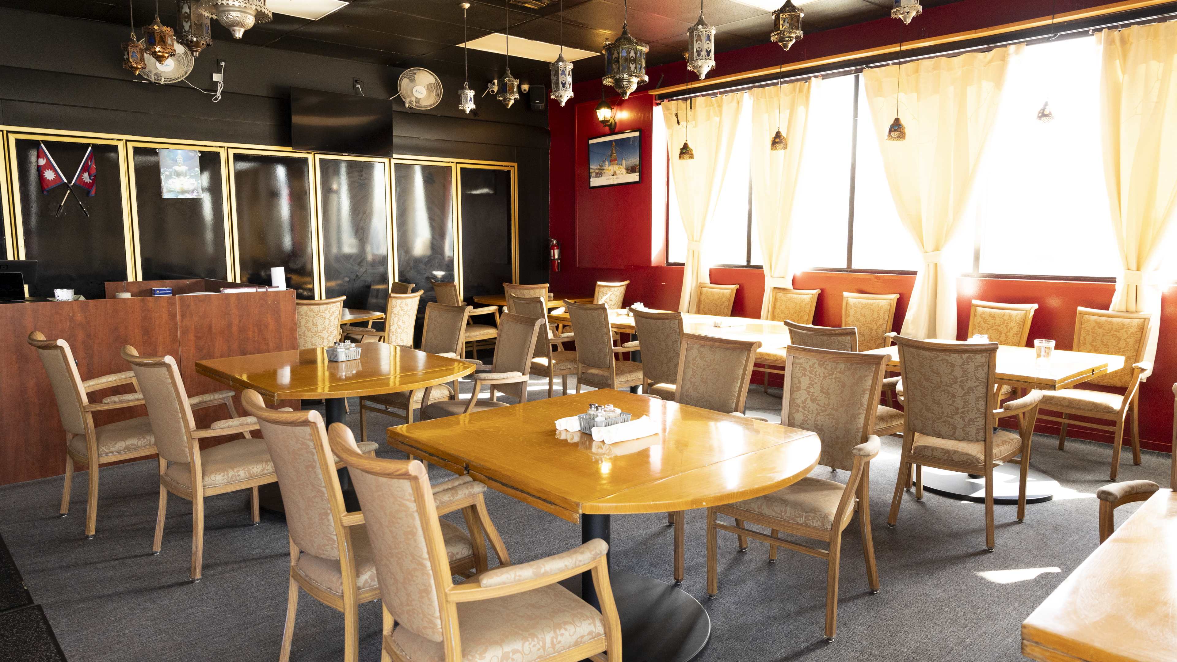 Dining room with whack and red walls, lanterns hanging from the ceiling, and wooden tables