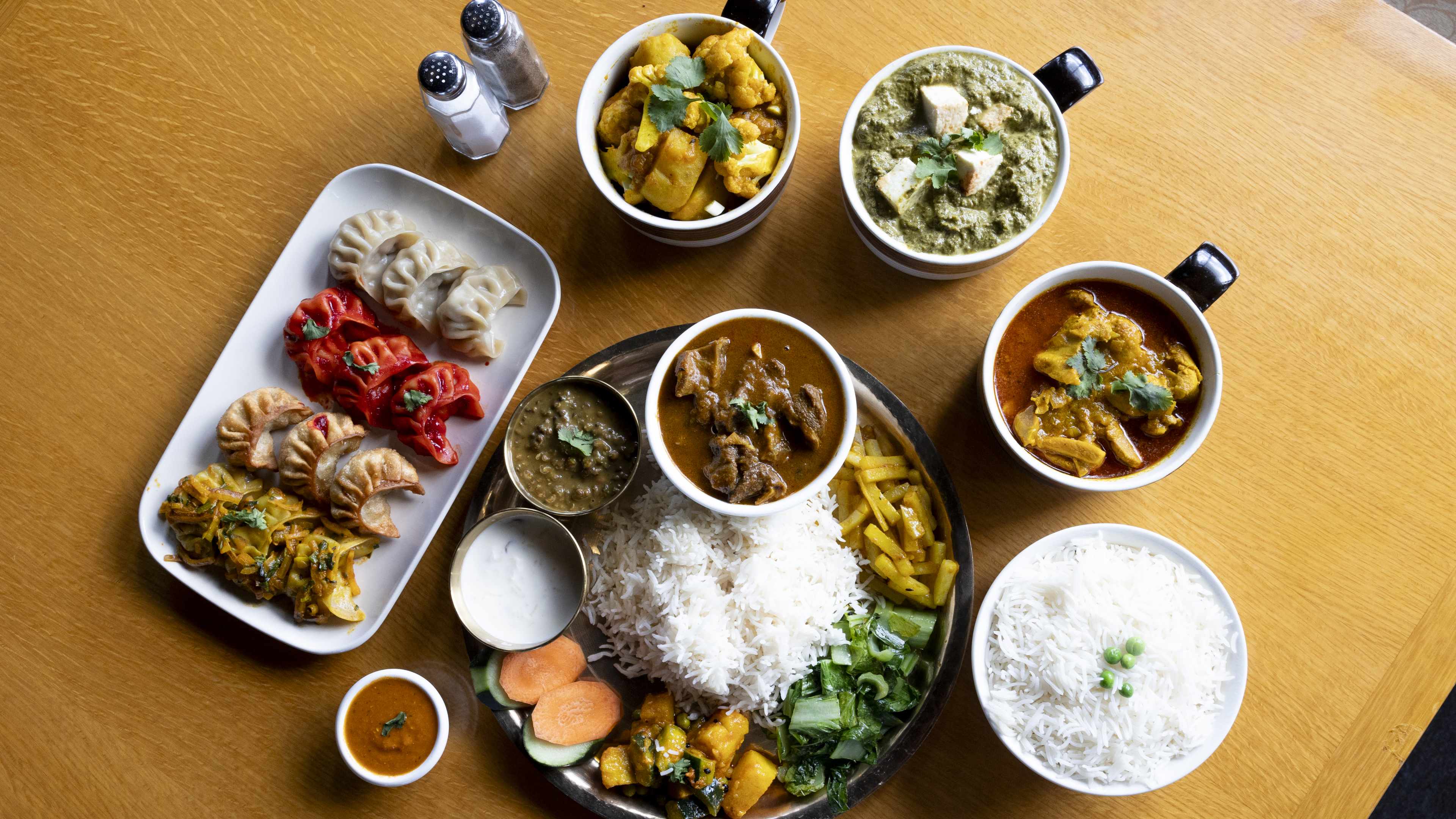 Spread of thali, momos, rice, curry, and saag paneer