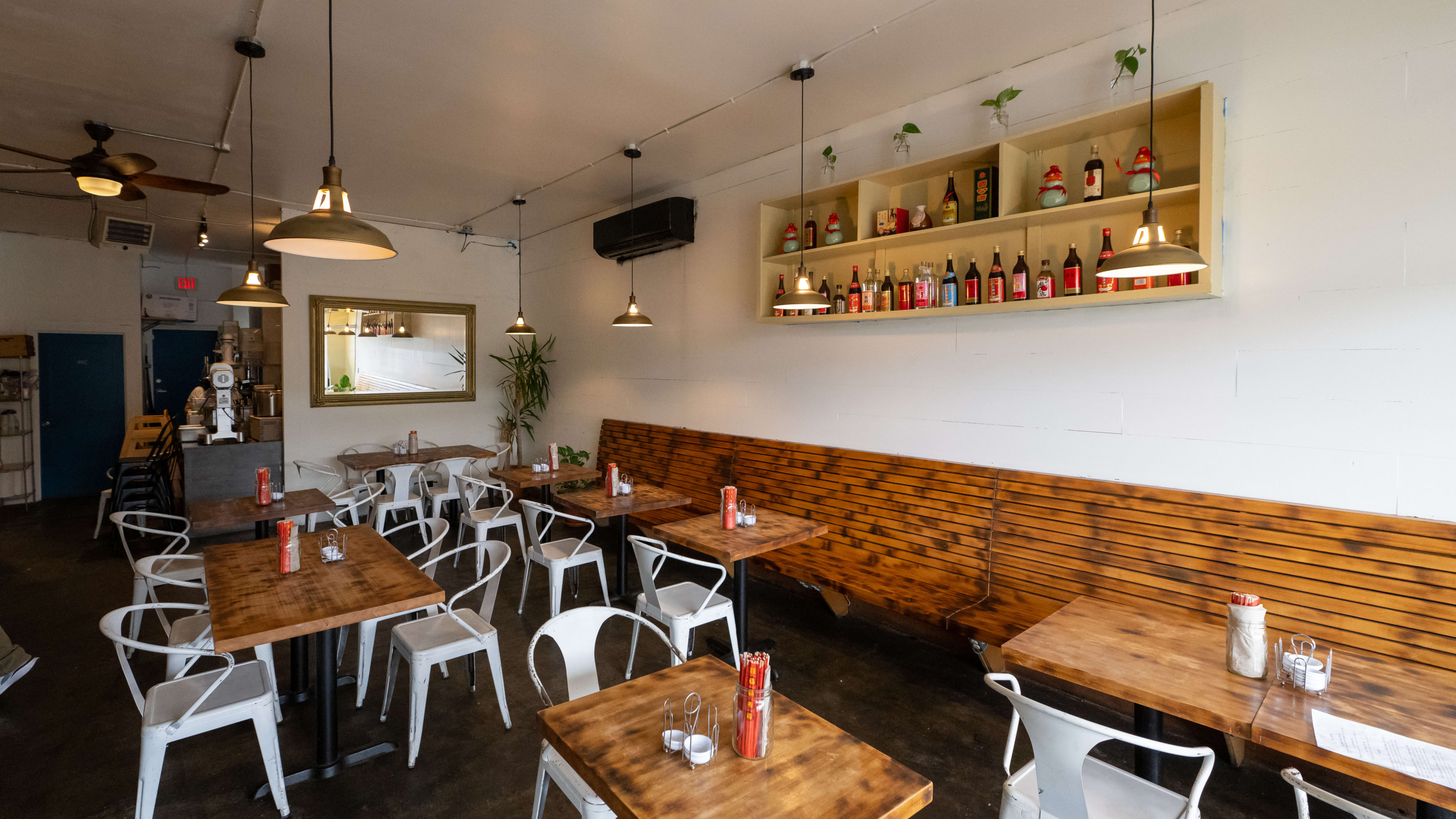 Dining room with wooden booths, white metal chairs, and chopstick holders on every table