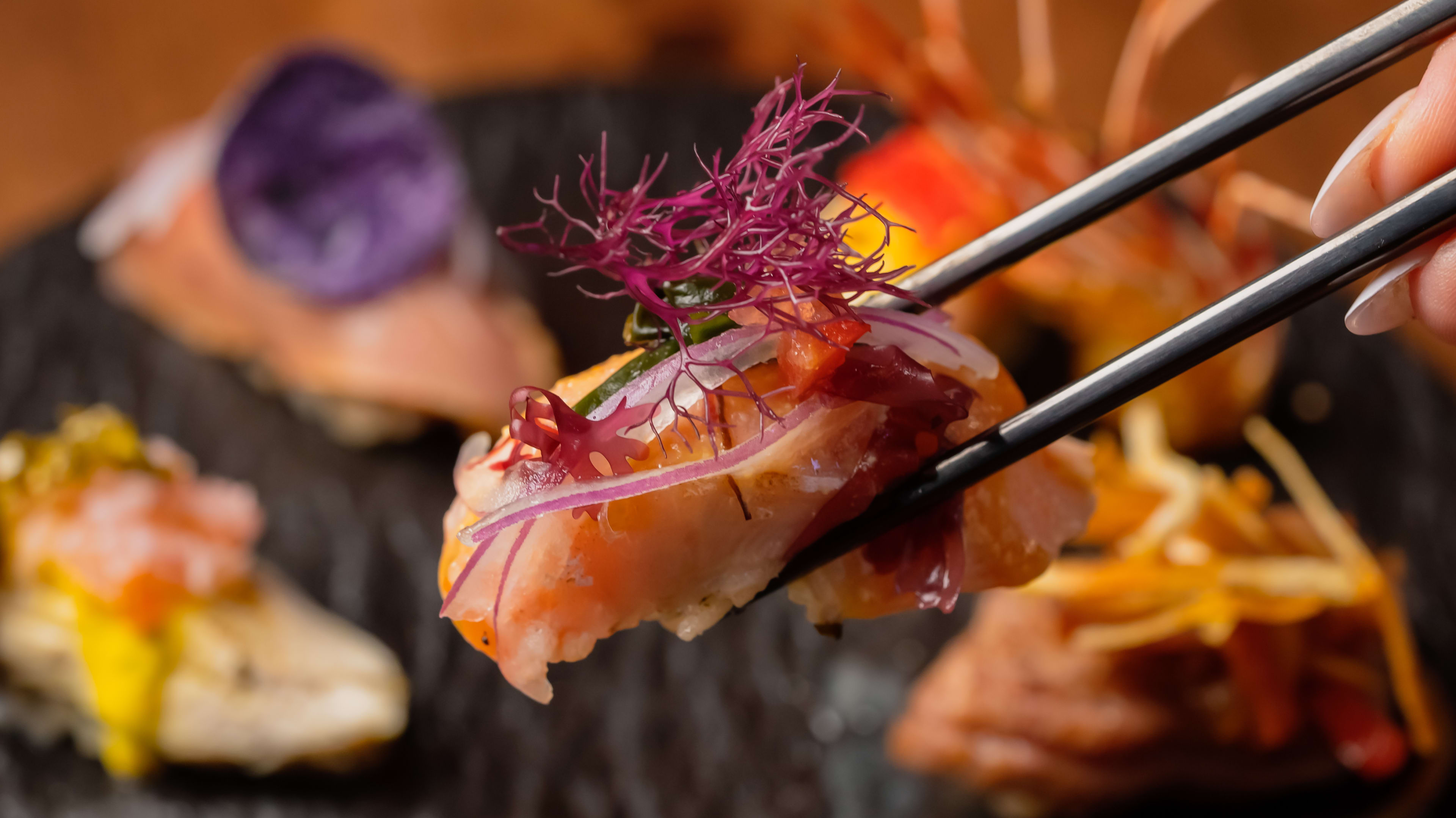 piece of salmon nigiri artfully topped with colorful ingredients