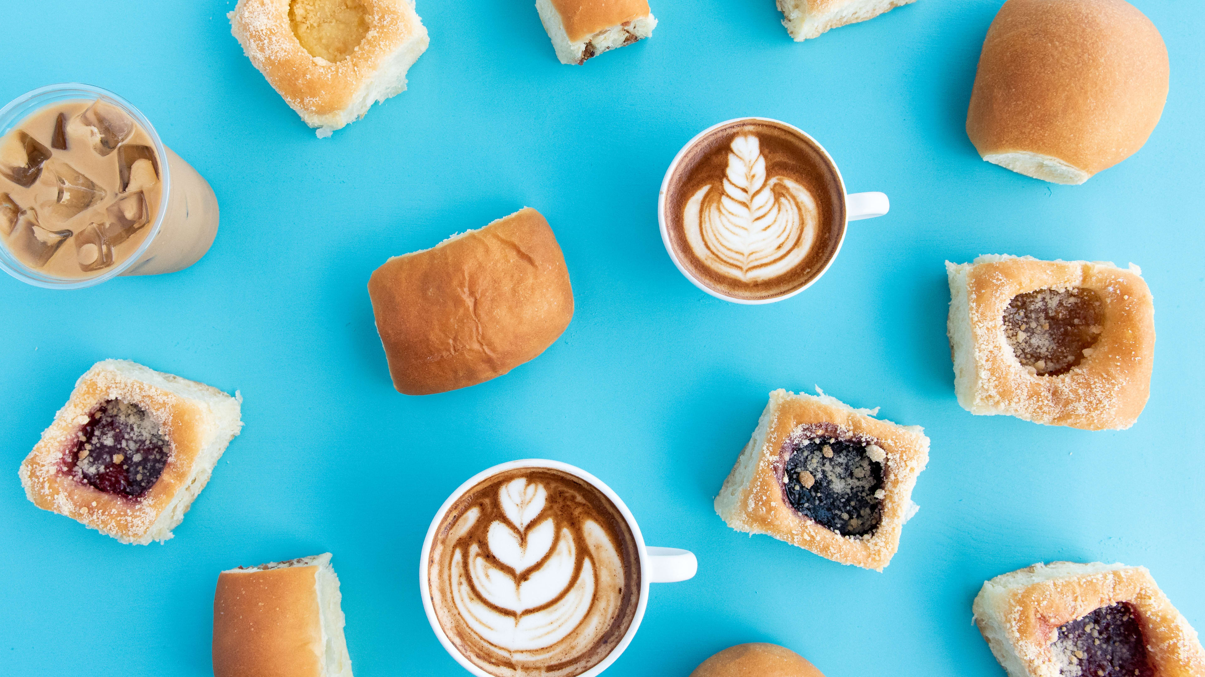 spread of multiple Kolache Shoppe kolaches with different coffee drinks