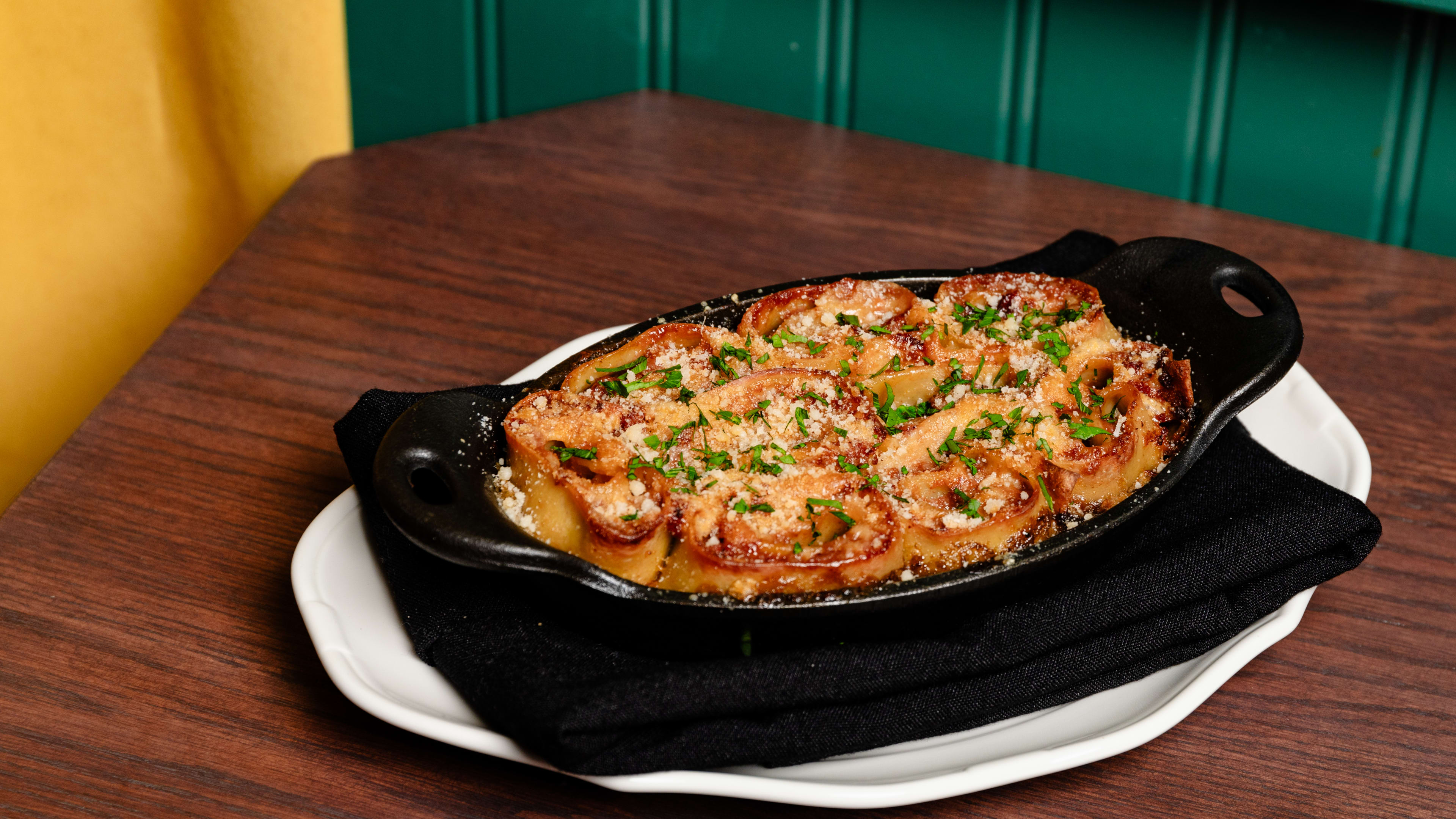 The pinwheel lasagna served in a cast iron skillet on a wooden table.