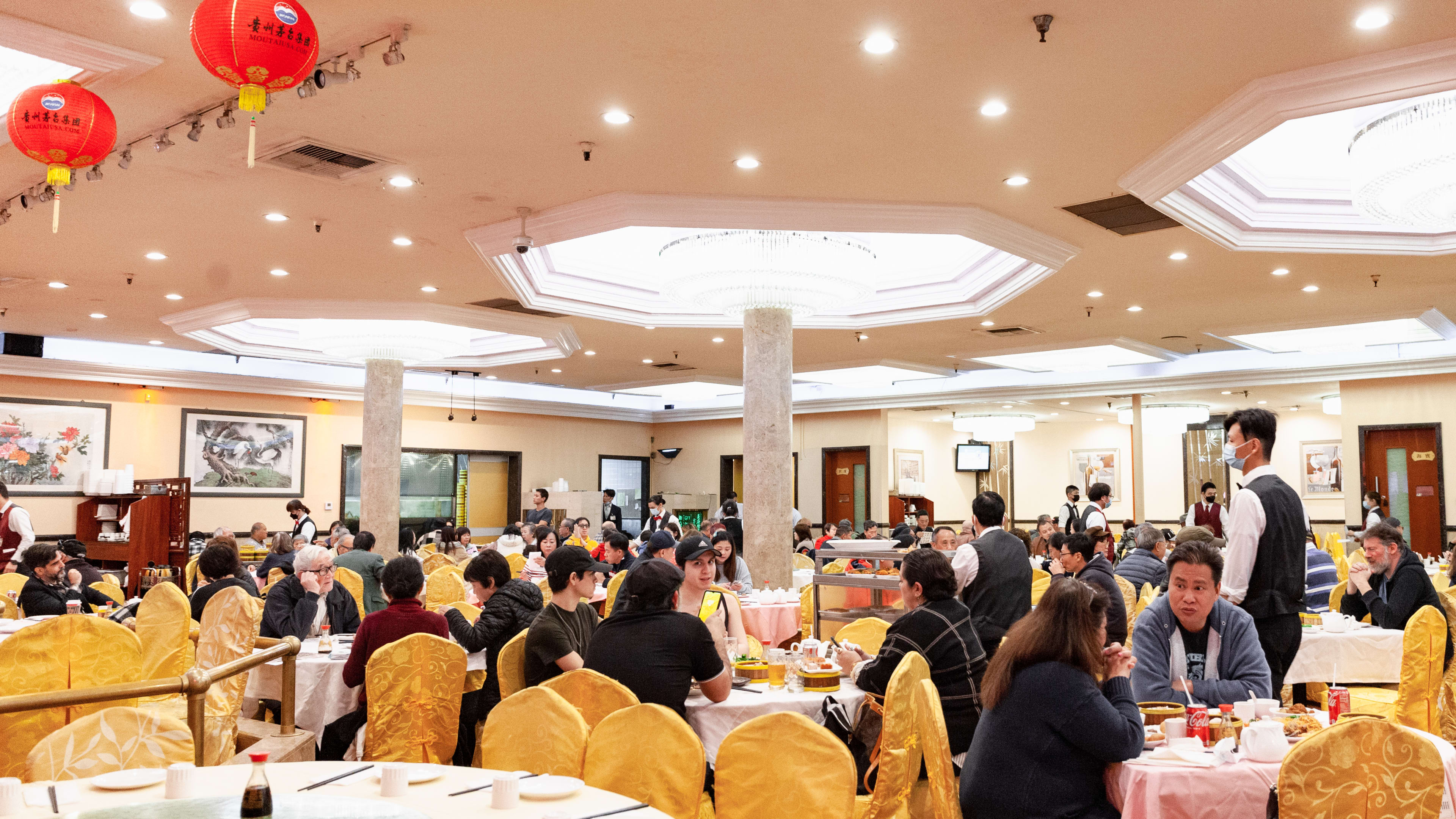 The large interior of NBC Seafood. There are round white tables with golden fabric covered chairs.