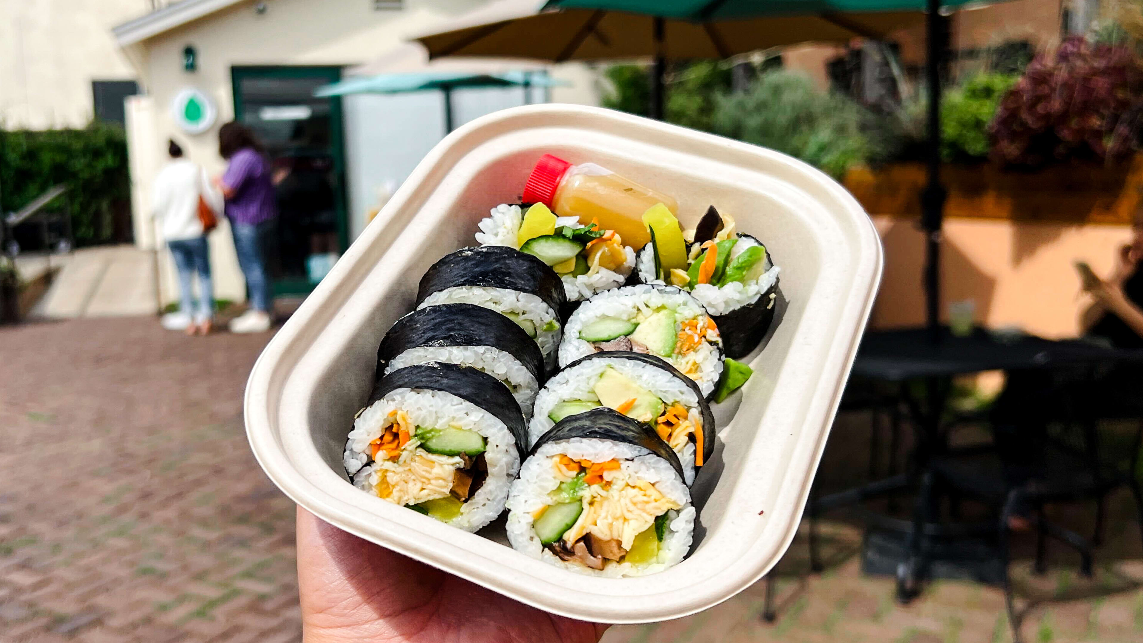 A takeway container of sushi held up.