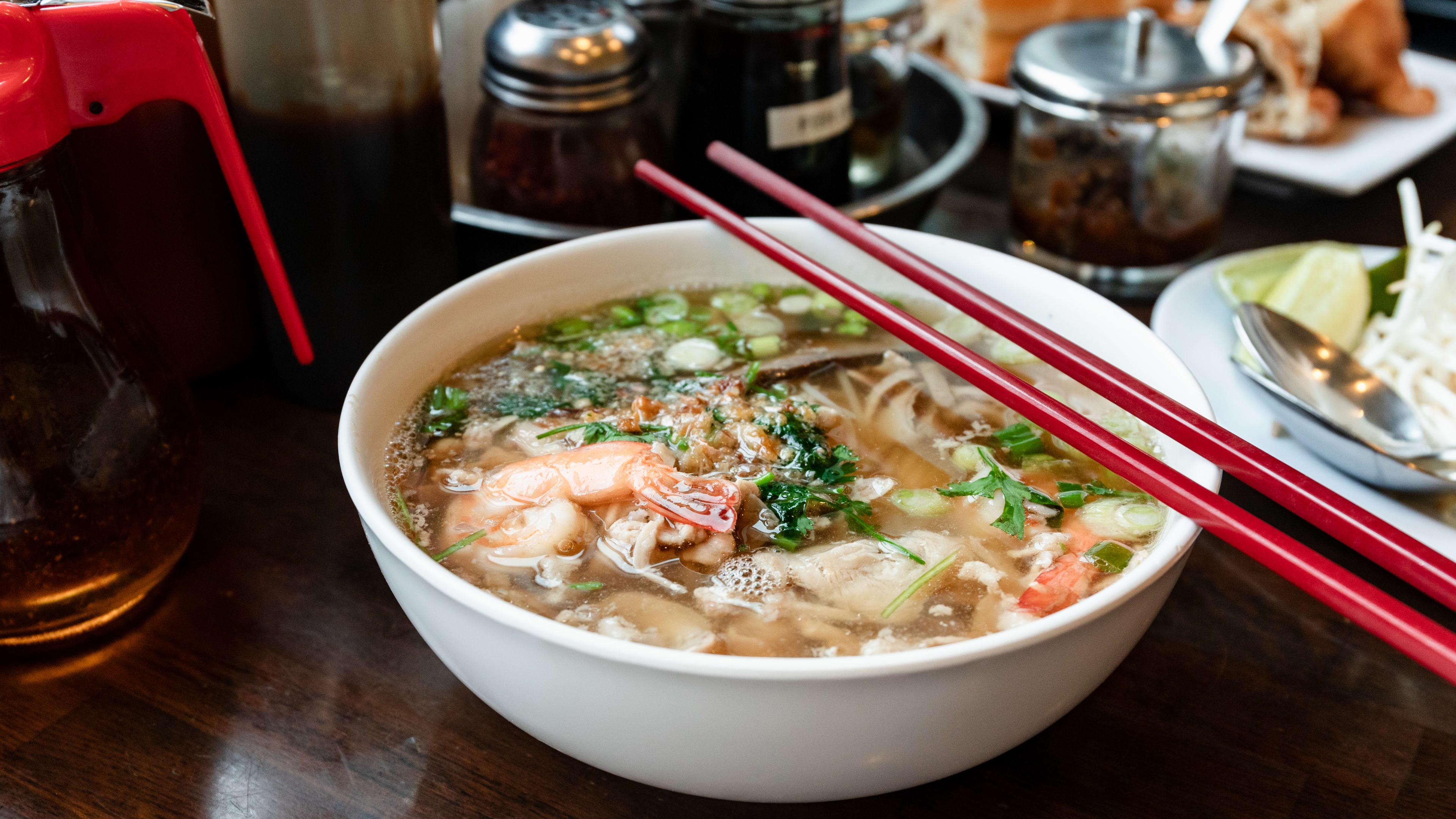 A bowl of the Phnom Penh house special soup with red chopsticks set on top.