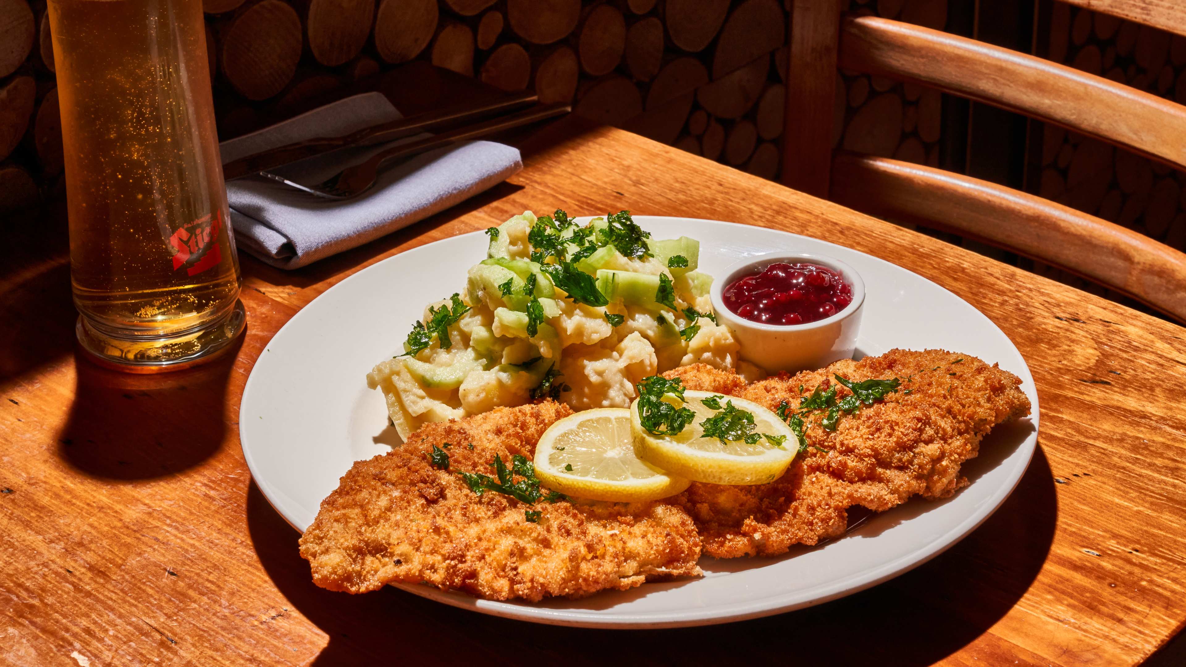 flat weiner schnitzel with lemon wedges, ketchup, and side salad