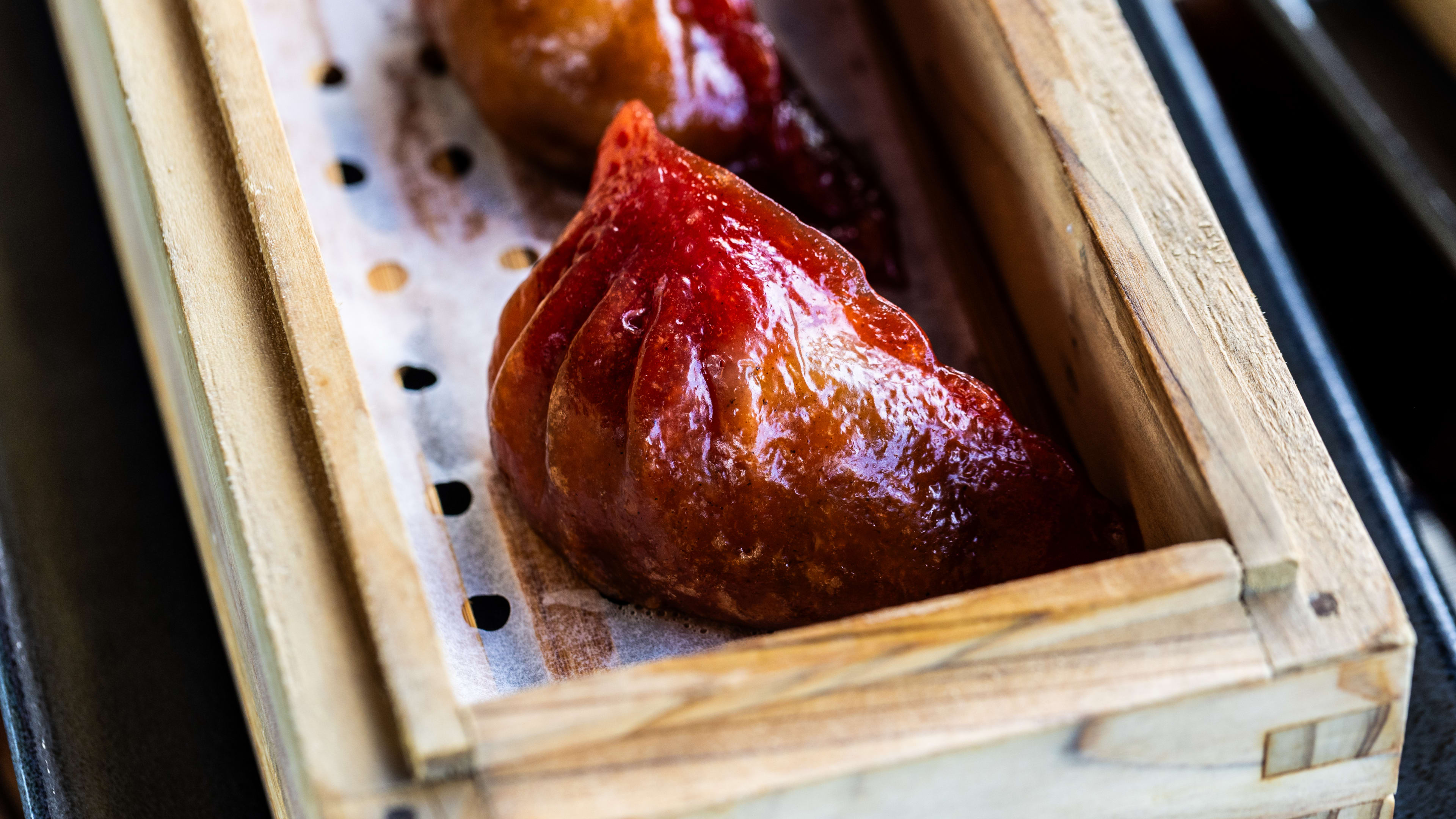 A crawfish dumpling in a wooden steamer box.