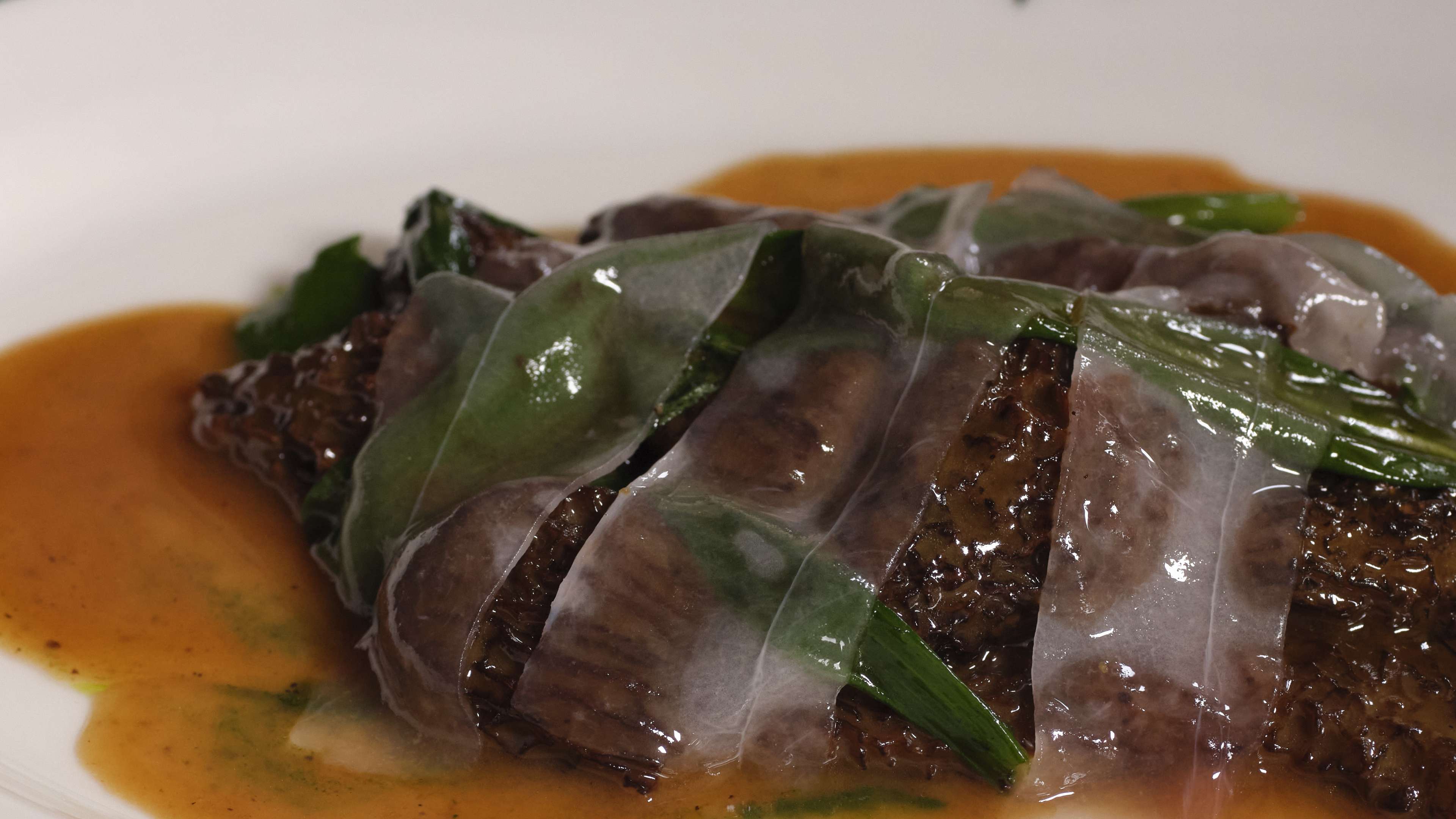 A close up of morel mushrooms draped in lardo from Lita.