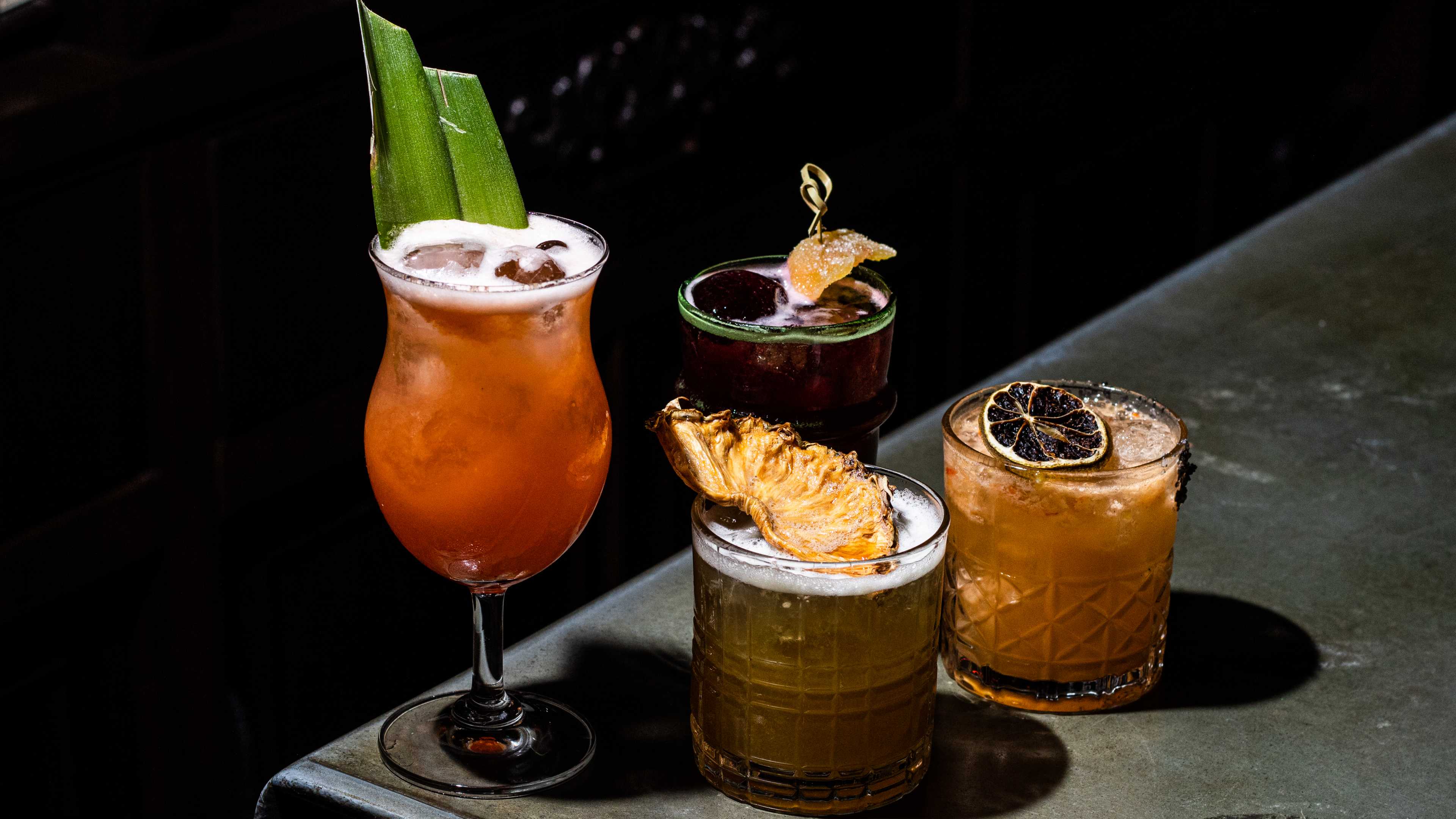 Four cocktails garnished with different fruits.