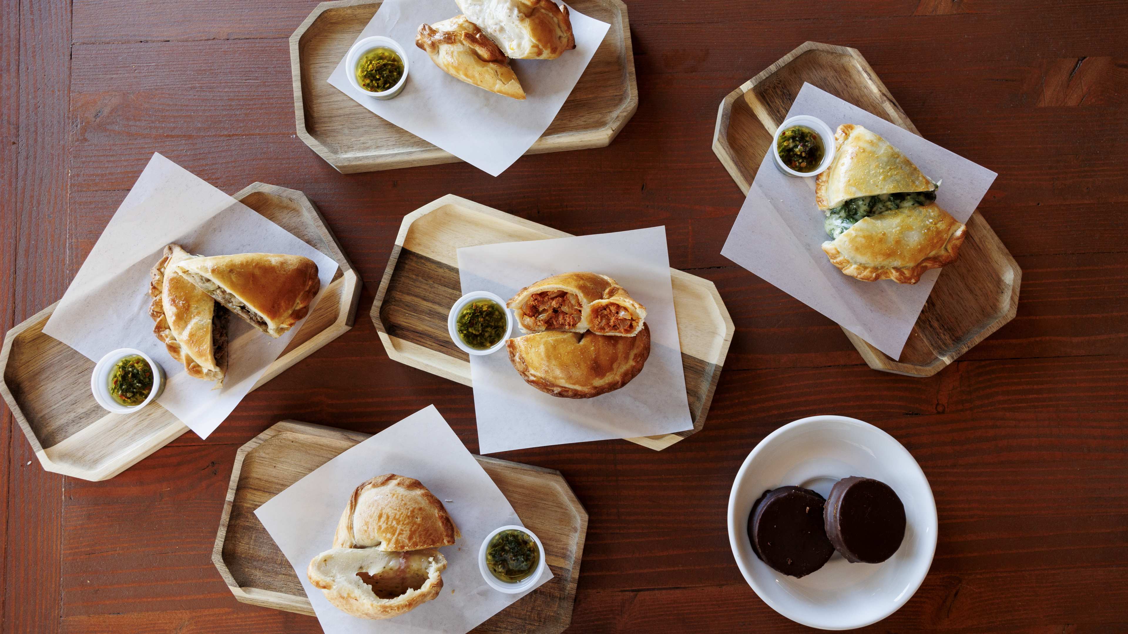 Assortment of empanadas cut in half, as well as chocolate alfajores