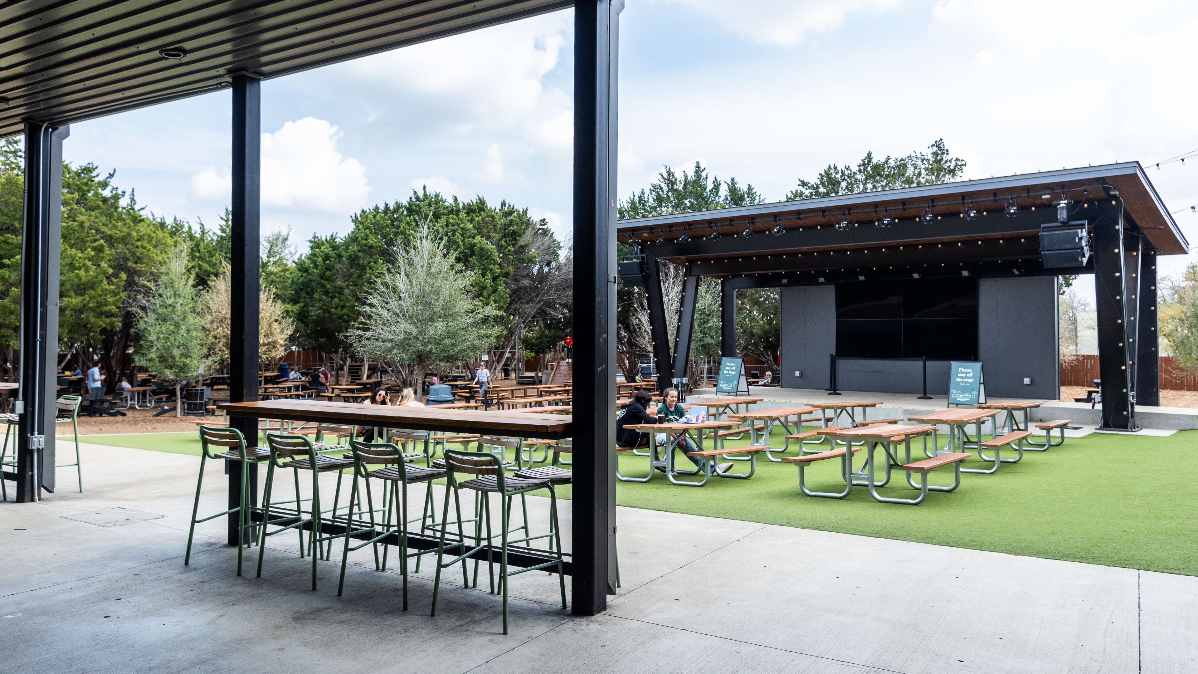 a patio with a stage and picnic tables